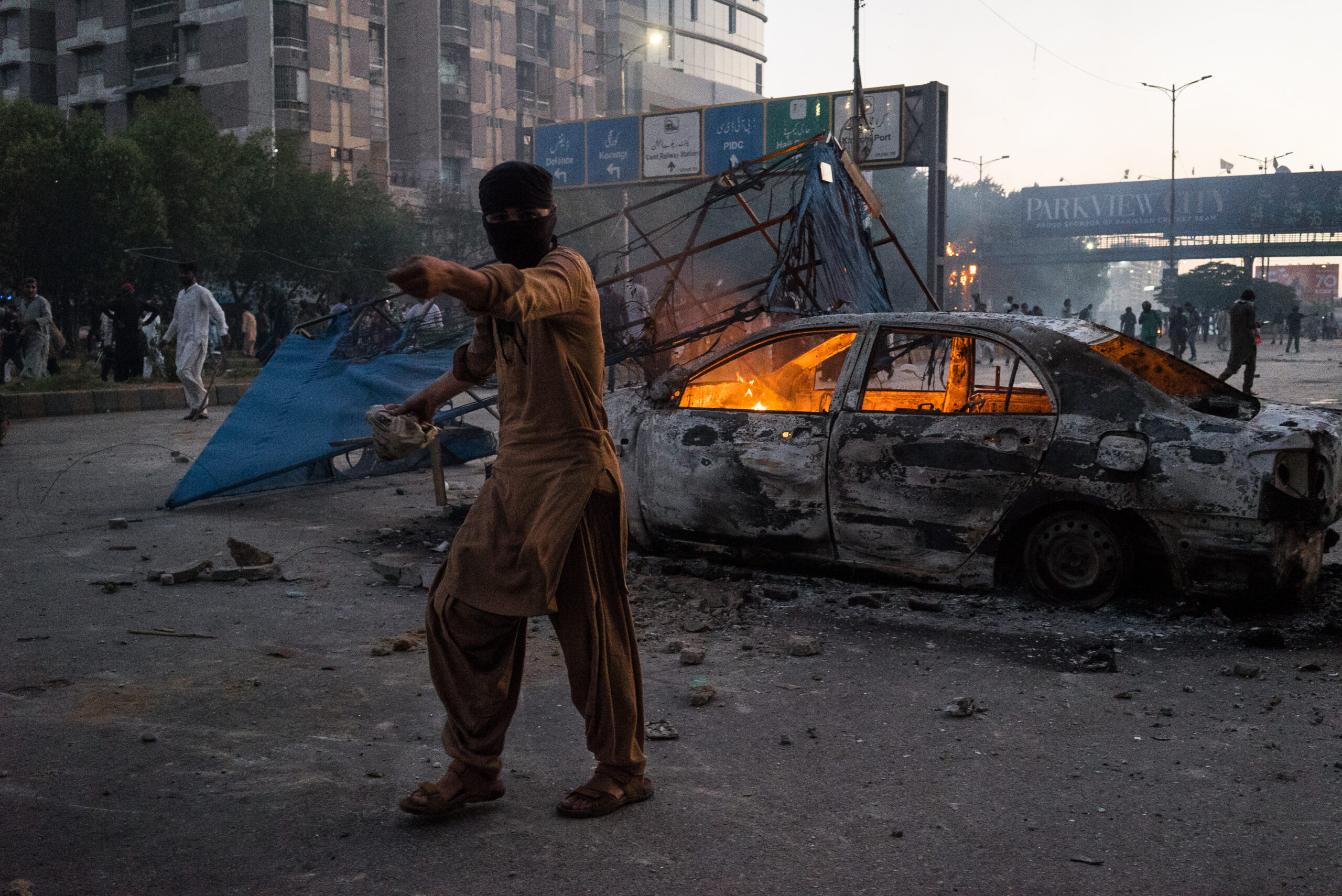 Simpatizante del PTI delante de un vehículo incendiado por manifestantes, Karachi, 9 de mayo. © Laurent Gayer