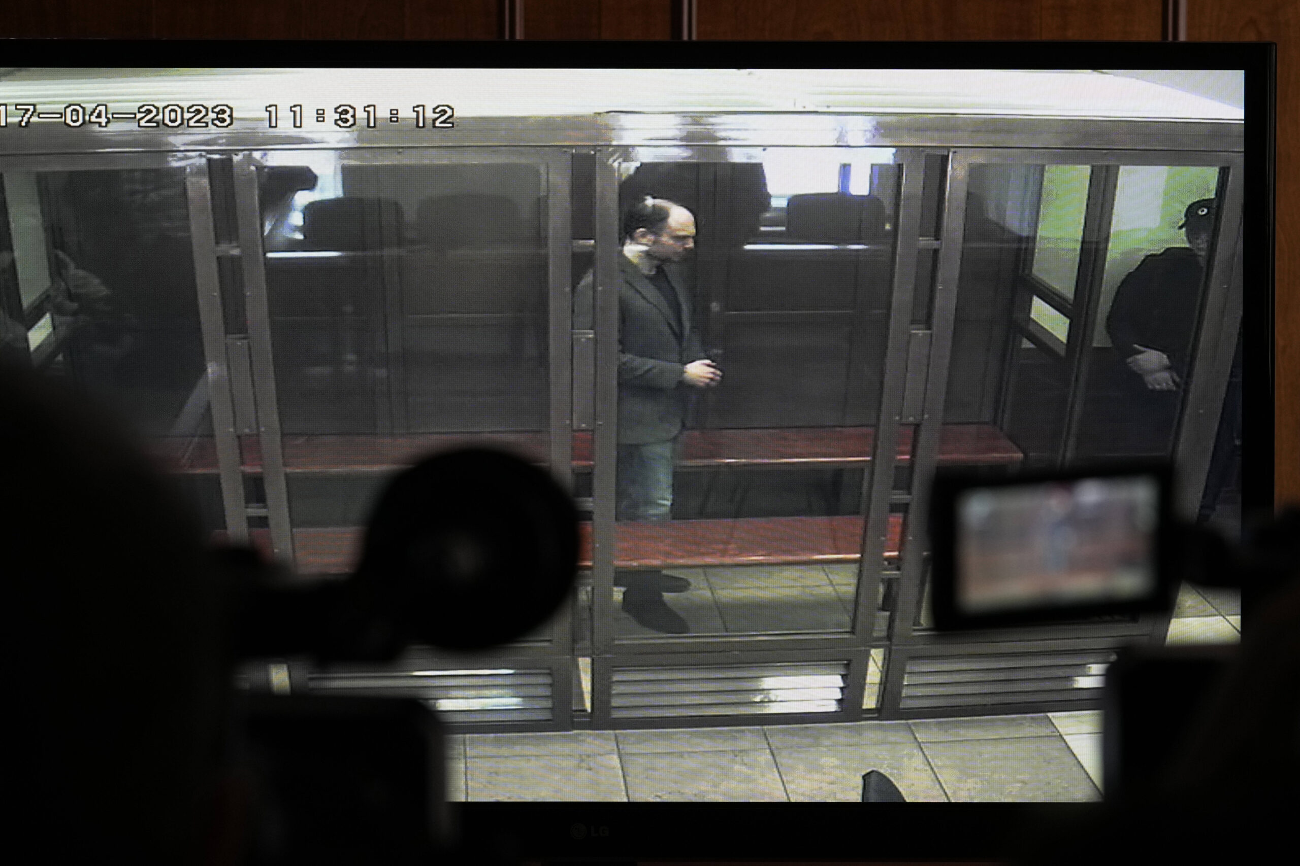 Vladimir Kara-Murza en una pantalla de televisión mientras permanece en una jaula de cristal mientras escucha el veredicto en una sala del Tribunal de la Ciudad de Moscú, en Moscú, Rusia, lunes 17 de abril de 2023. The Moscow City Court via AP