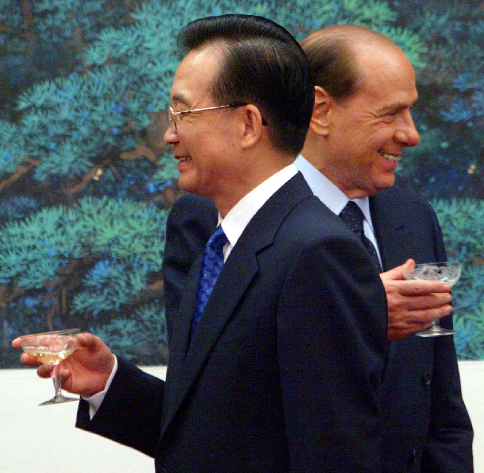 El Primer Ministro chino Wen Jiabao, en primer plano, y su homólogo italiano Silvio Berlusconi pasan uno junto al otro tras un brindis en una ceremonia de firma en Pekín, el viernes 31 de octubre de 2003. © AP Foto/Guang Niu, Pool