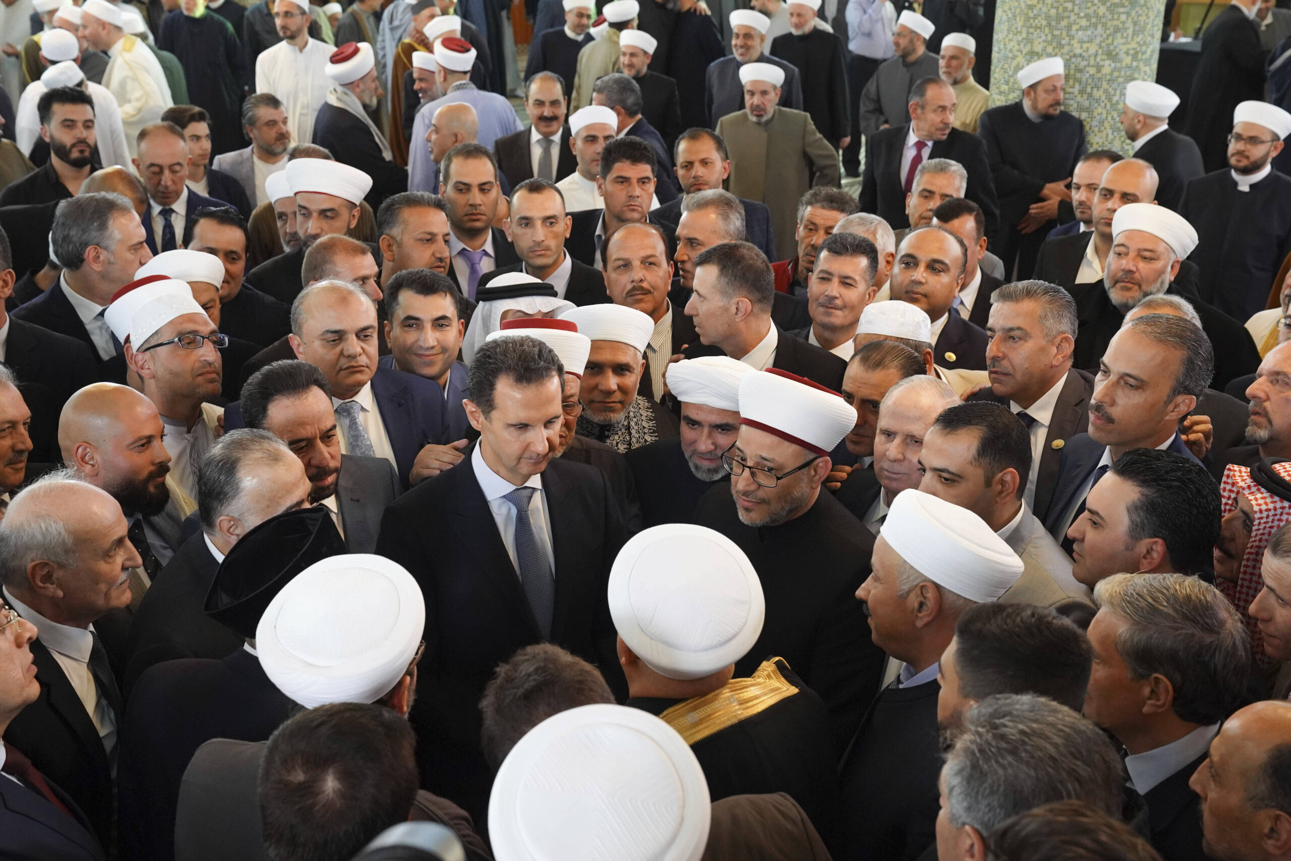 En esta foto difundida por la agencia de noticias oficial siria SANA, el presidente sirio Bashar Assad, en el centro, saluda a clérigos sirios tras las oraciones del Eid al-Fitr, que marcan el final del mes sagrado musulmán del Ramadán, el viernes 21 de abril de 2023. © AP Foto