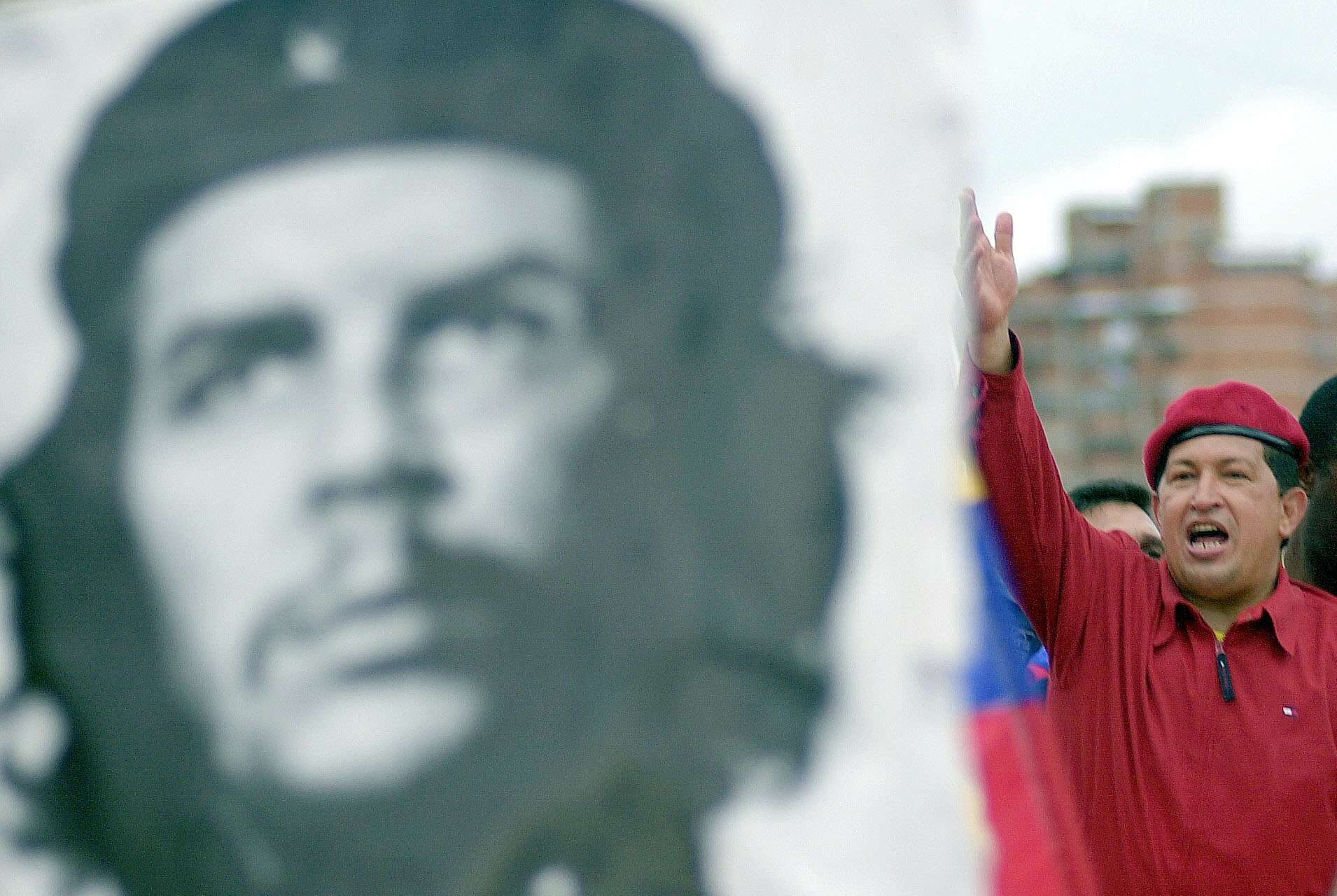 El presidente venezolano Hugo Chávez saluda a sus seguidores junto a un póster del héroe revolucionario cubano Ernesto «Che» Gevara. 29 de junio de 2002. © AP Foto/Fernando Llano