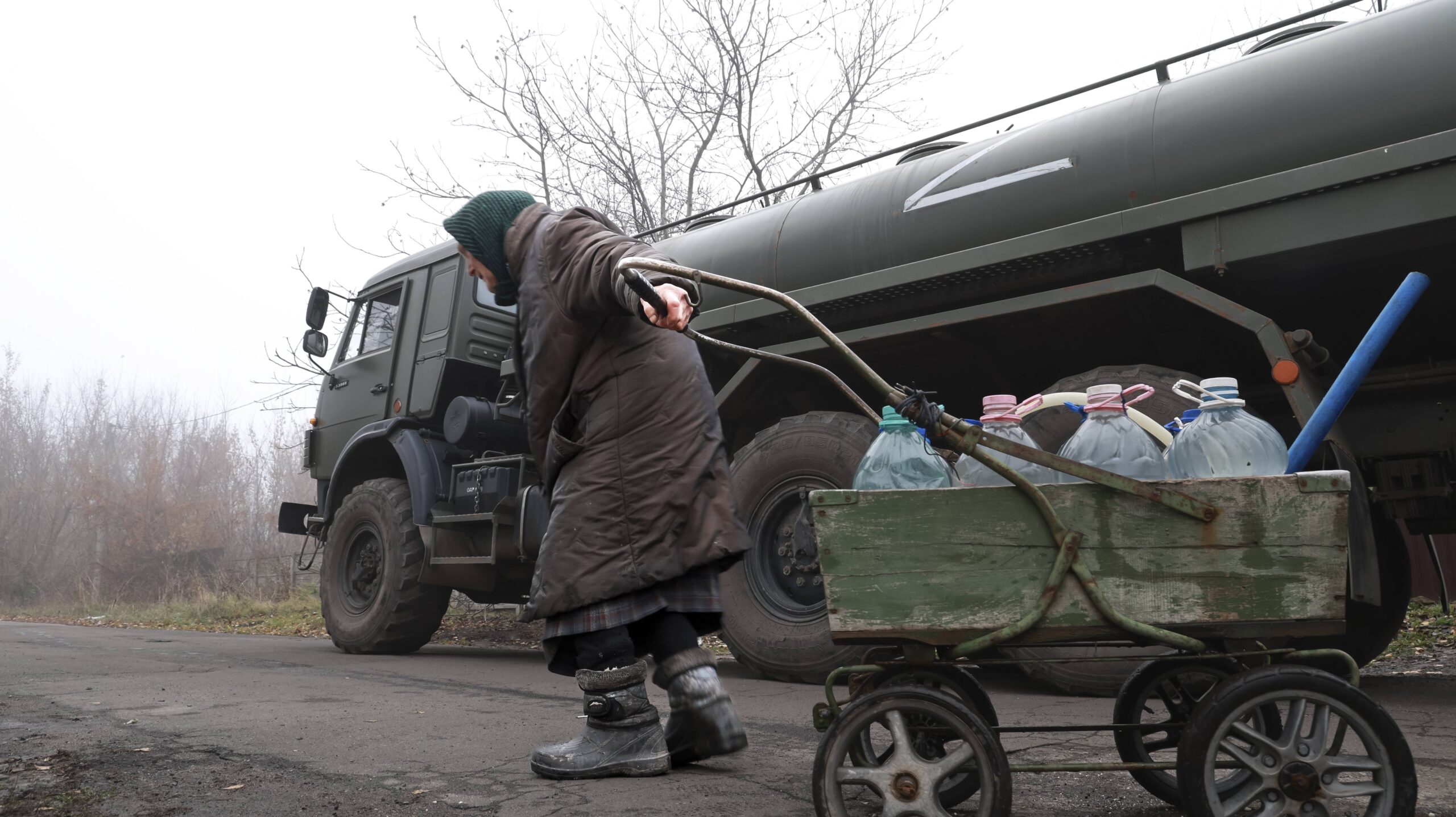 Una persona mayor tira de un carro que contiene agua embotellada distribuida por el ejército ruso a las afueras de Donetsk, Ucrania, viernes 10 de noviembre de 2023. © AP Photo/Alexei Alexandrov