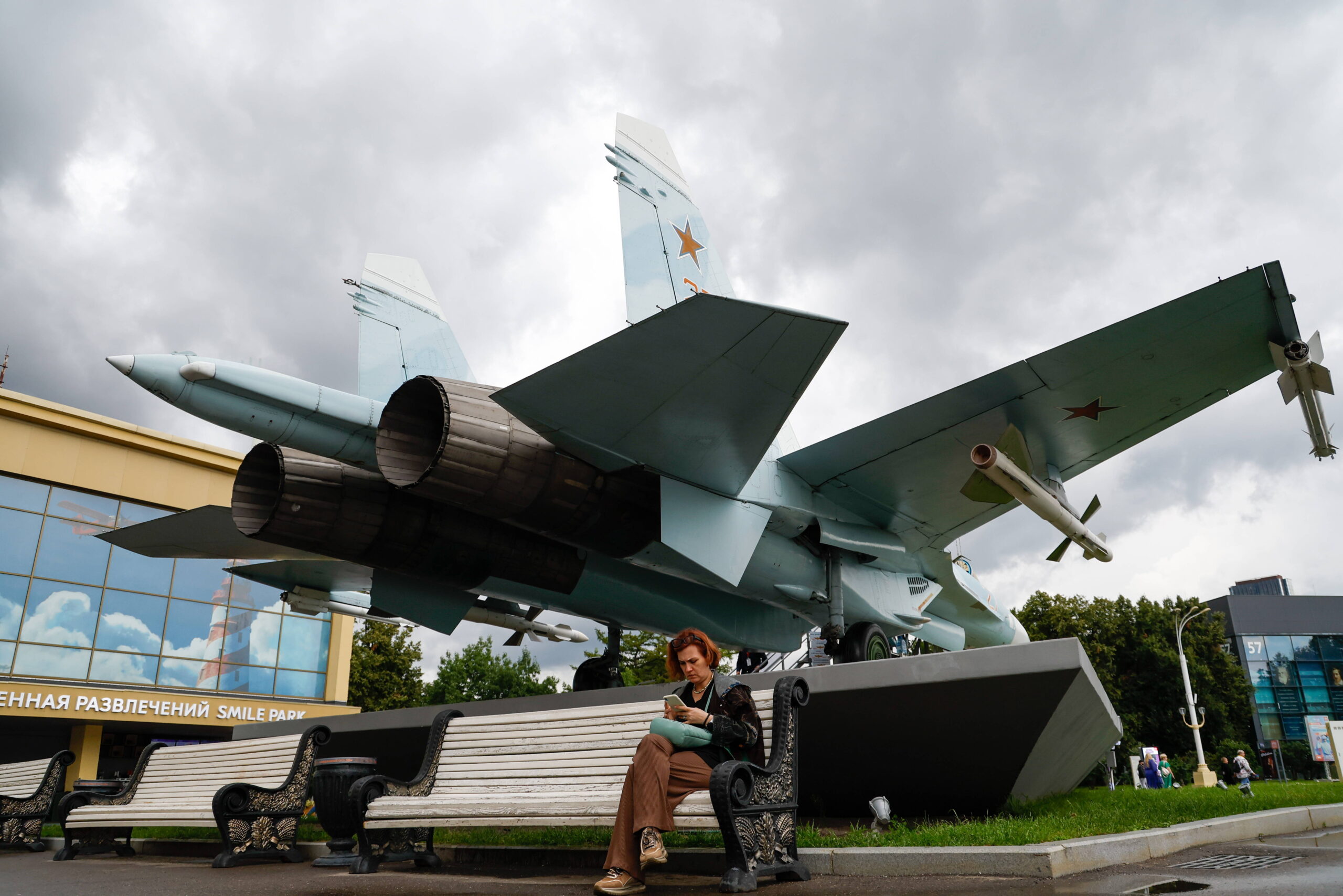 Una mujer sentada en un banco junto a un caza Sukhoi Su-27 en el centro de exposiciones VDNKh. Moscú, Rusia, 1 de agosto de 2024 © Mikhail Sinitsyn/TASS/Sipa USA