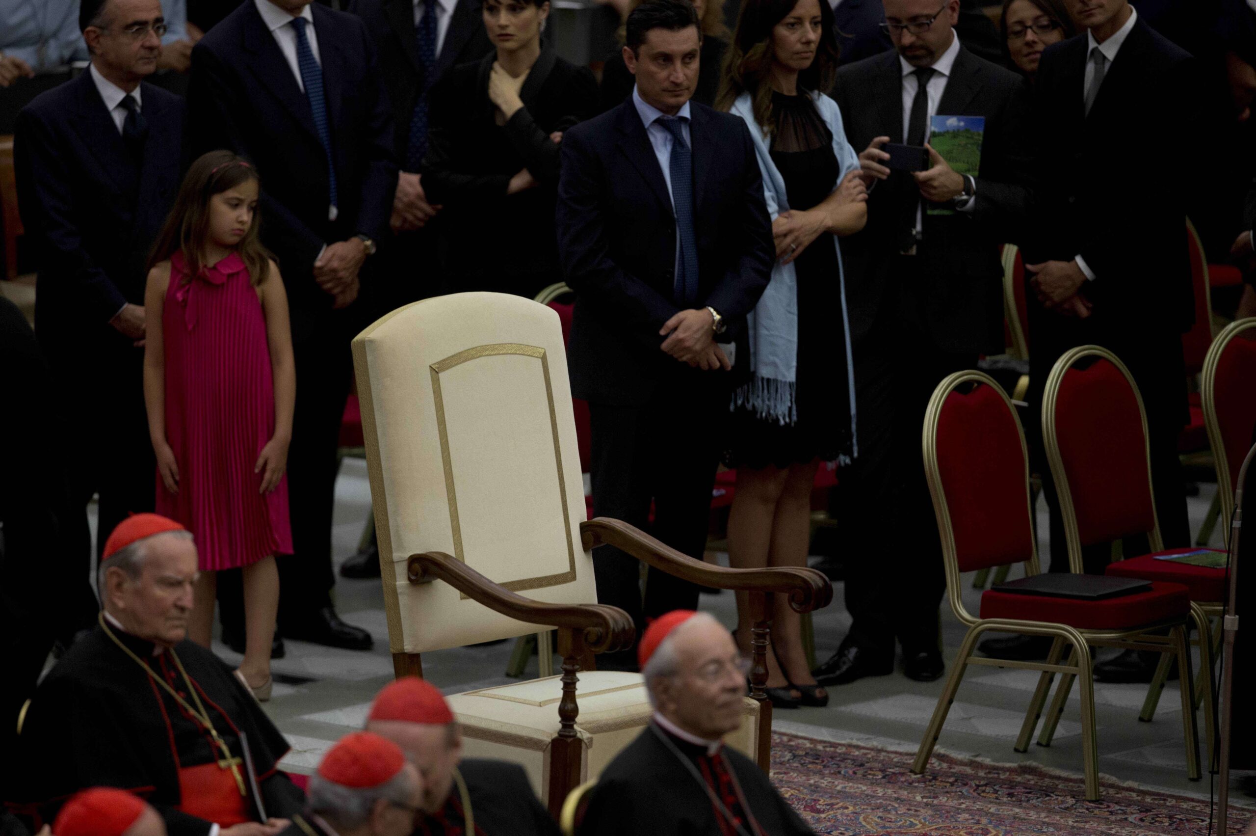 Cardenales, a la izquierda, sentados junto a la silla vacía del papa Francisco, escuchan a monseñor Rino Fisichella, no visible, leer un mensaje del pontífice antes del inicio del concierto dirigido por el director eslovaco Juraj Valcuha Mehta con la Orquesta de la RAI (televisión estatal italiana), en el Aula Pablo VI del Vaticano, el sábado 22 de junio de 2013. © AP Photo/Alessandra Tarantino