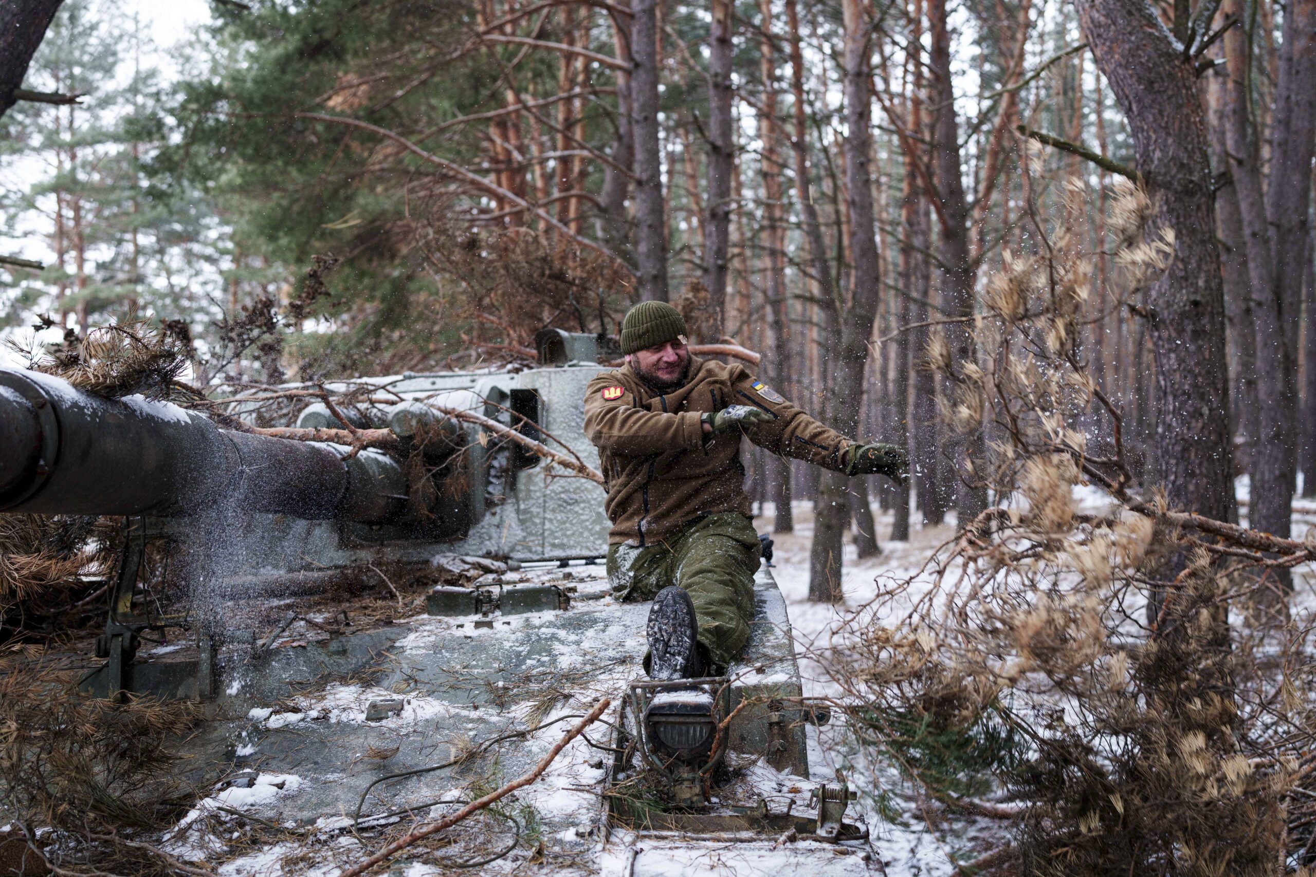 Leonid Lobchuk, soldado de la 127 brigada ucraniana que perdió una pierna en combate en el este de Ucrania en 2015, retira el camuflaje de su obús autopropulsado en la región ucraniana de Jarkov el 10 de febrero de 2025. © AP Photo/Evgeniy Maloletka