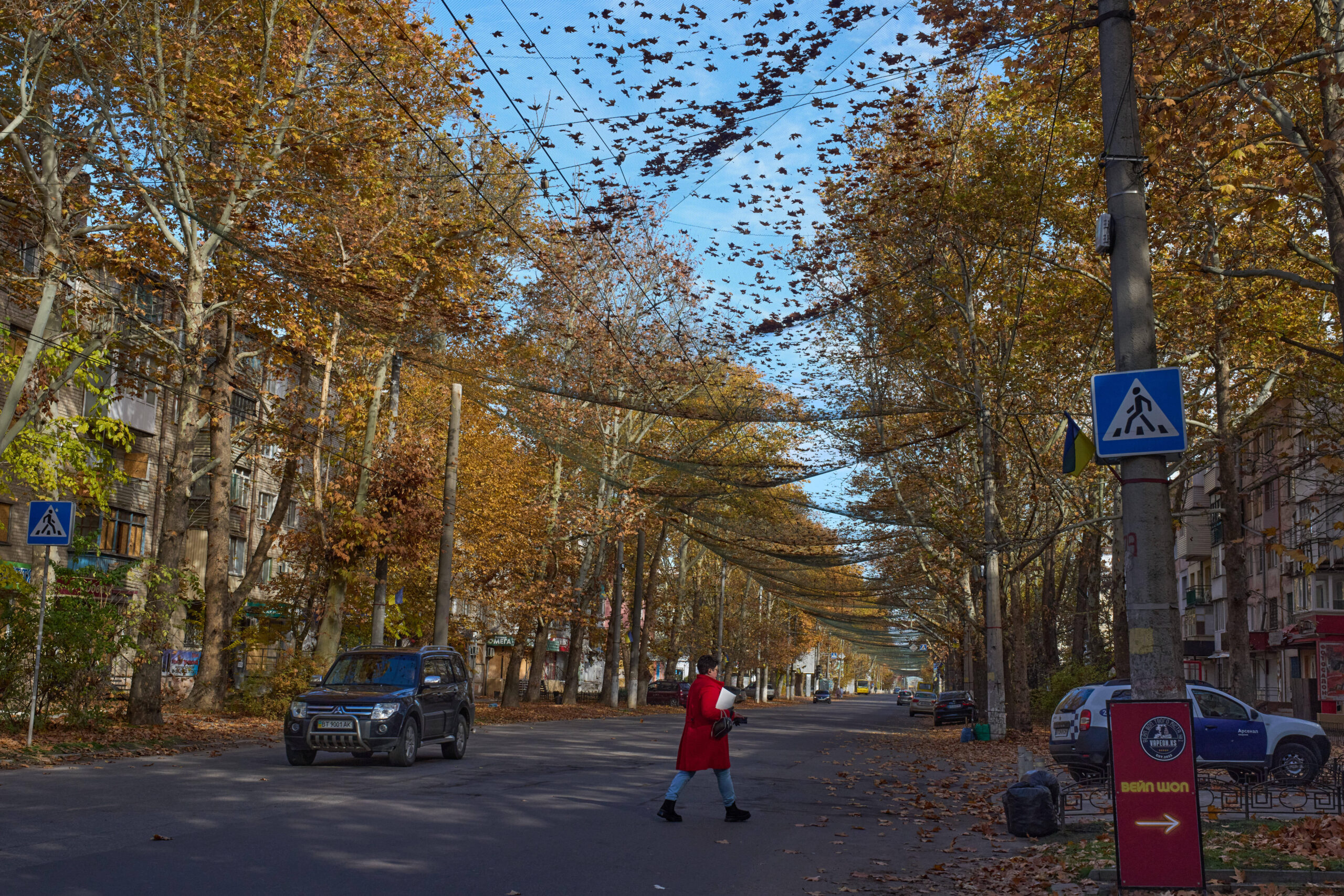 Un habitante cruza la calle cubierta por una red antidrones FPV en la ciudad de Jersón, cerca de la línea del frente, el lunes 3 de noviembre de 2025. © AP Photo/Efrem Lukatsky