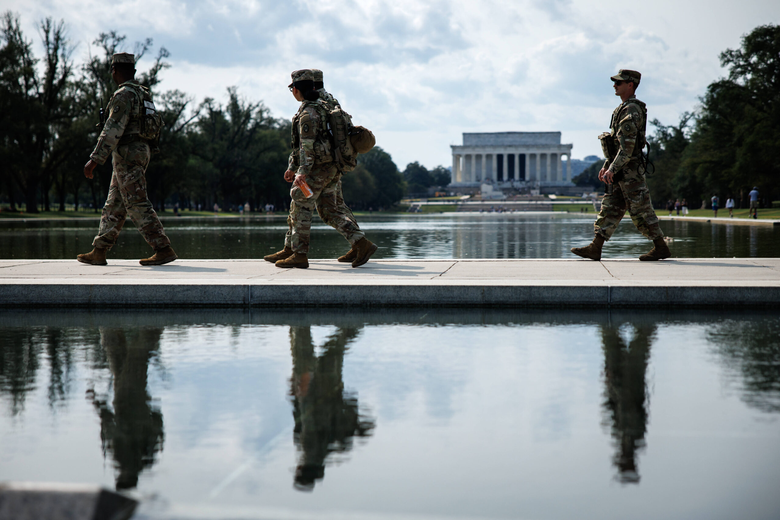 Miembros de la Guardia Nacional patrullan el 5 de septiembre de 2025 en el National Mall, recorriendo el camino entre el Monumento a la Segunda Guerra Mundial y el Reflecting Pool, en Washington. Esta presencia se produce después de que el presidente Trump haya firmado un decreto por el que se renombra el Departamento de Defensa como Departamento de Guerra, mientras las tropas continúan con sus misiones de seguridad en la capital federal. © Samuel Corum