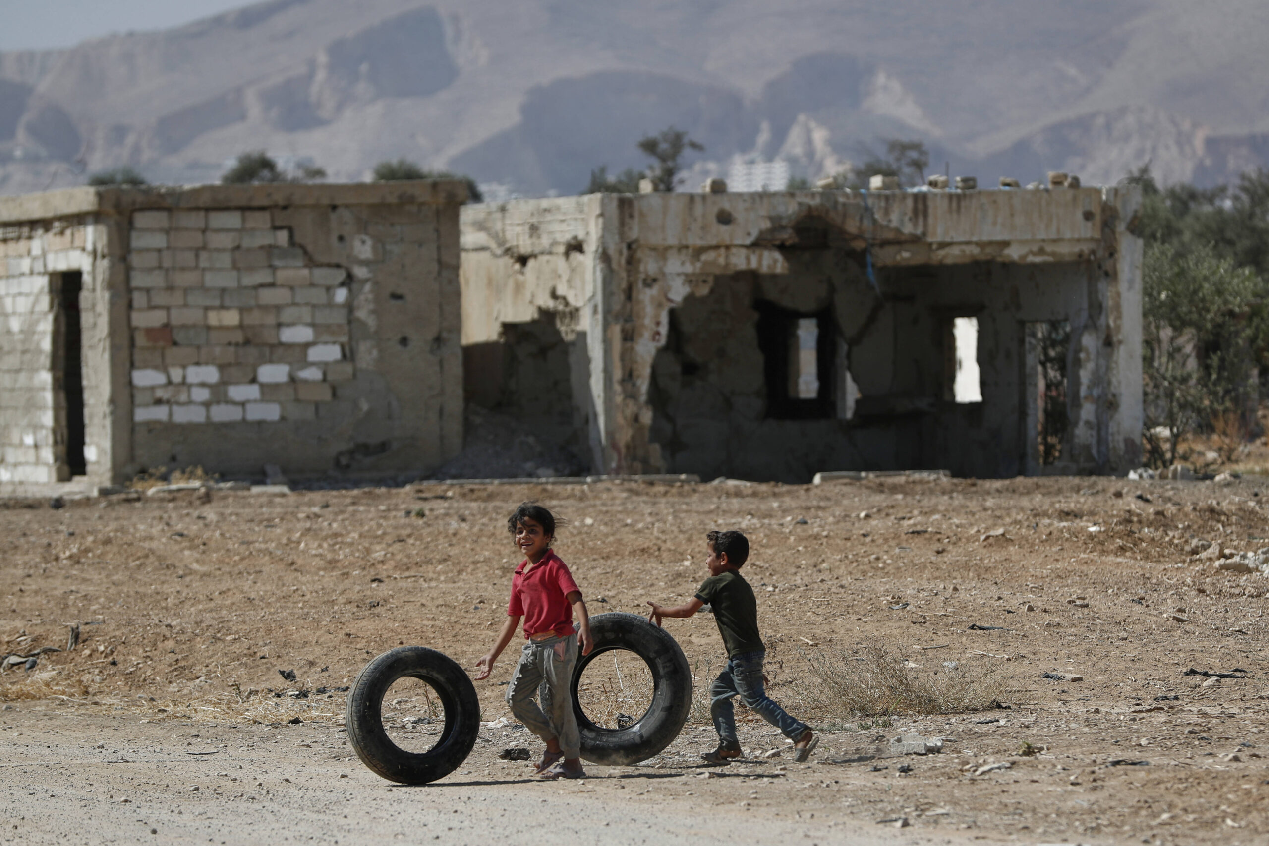 Niños sirios juegan con llantas viejas en la ciudad de Duma, Siria, devastada por la guerra, el martes 16 de septiembre de 2025. © AP Photo/Omar Sanadiki