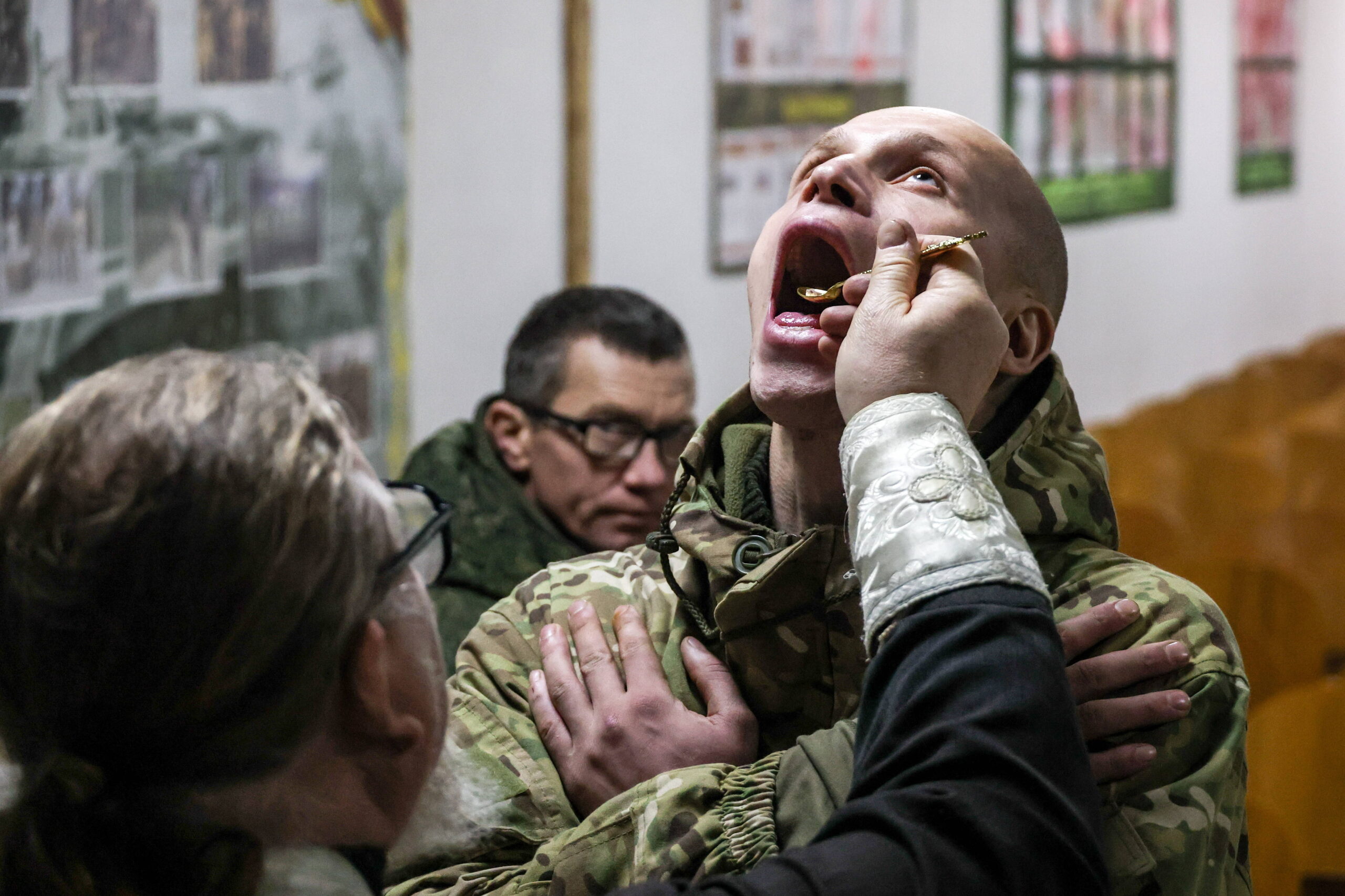 Un sacerdote da la comunión a un soldado del 291.º Regimiento Motorizado de la Guardia del Grupo de Fuerzas Rusas Dnepr tras una misa de Navidad en el frente de Zaporizhia. © Alexander Polegenko
