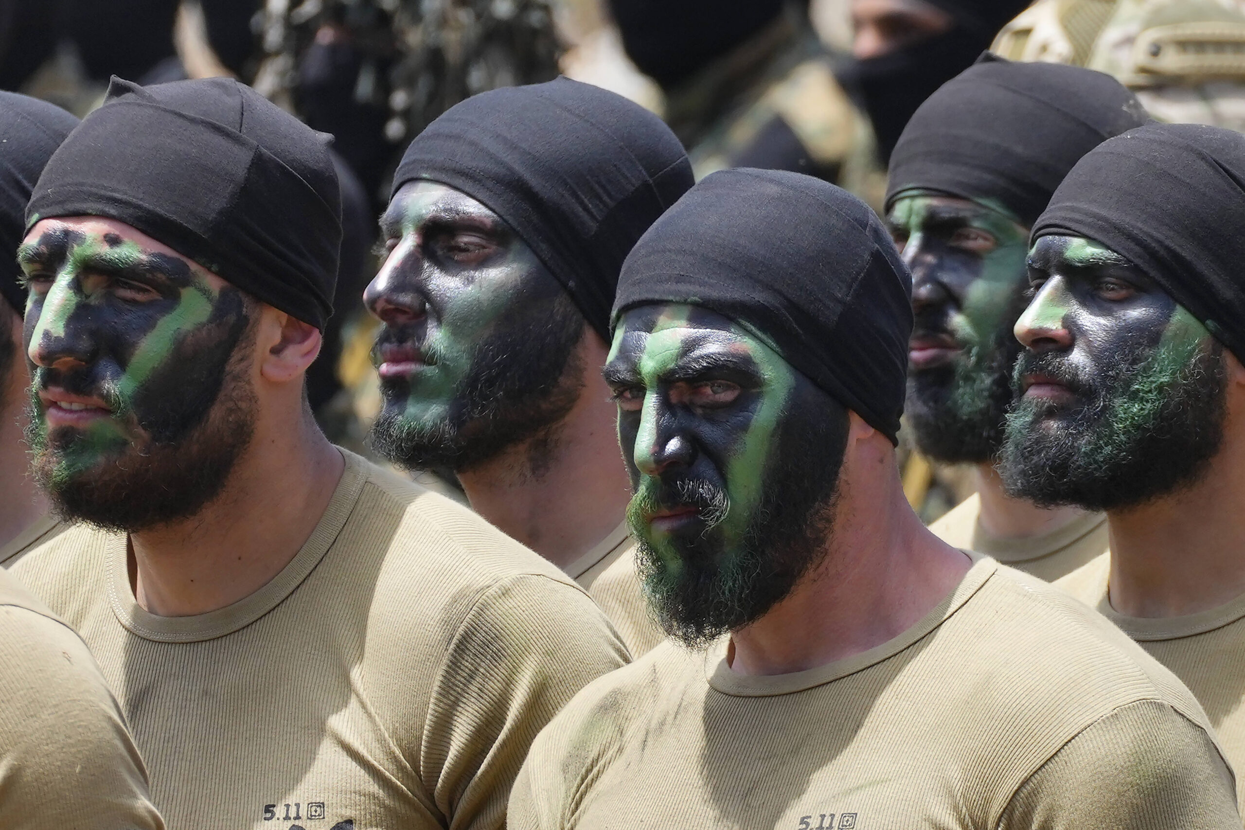 Combatientes de Hezbolá con los rostros pintados con motivos de camuflaje durante un entrenamiento. © AP Foto/Hassan Ammar