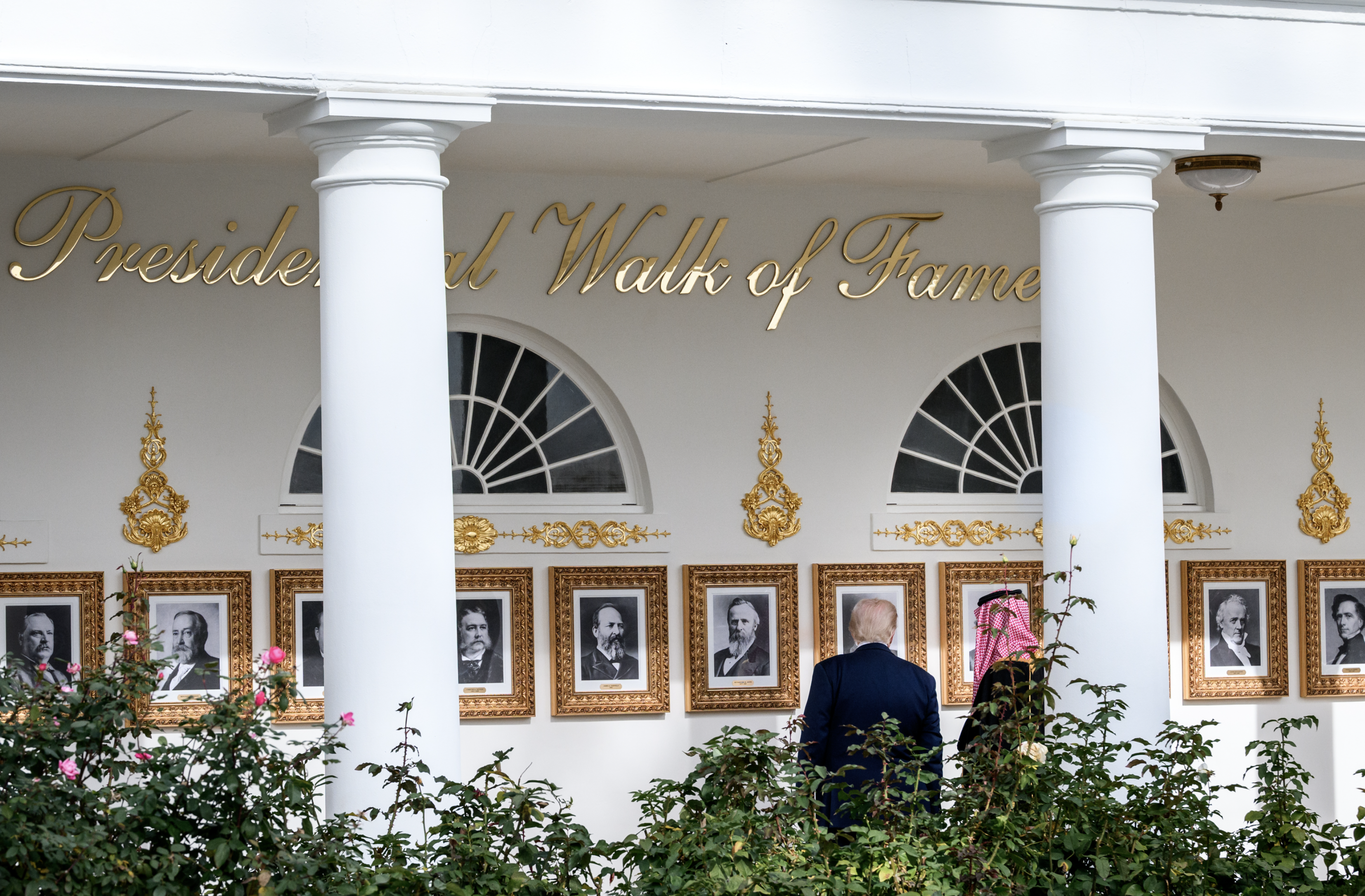 Donald Trump y su anfitrión recorren la columnata del jardín de rosas, reconvertida en el «Presidential Walk of Fame»: retratos de los presidentes en marcos dorados bajo un letrero con letras cursivas doradas. Foto oficial de la Casa Blanca