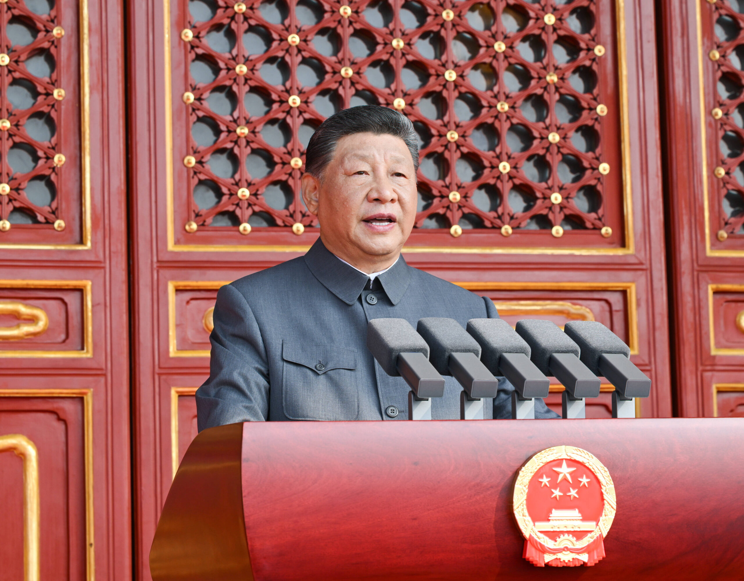 Cuello Mao gris, cinco micrófonos, laca roja y el emblema nacional: el retrato oficial difundido por China retoma la iconografía maoísta, incluso en el encuadre ligeramente en contrapicado que realza la figura del orador. Foto oficial