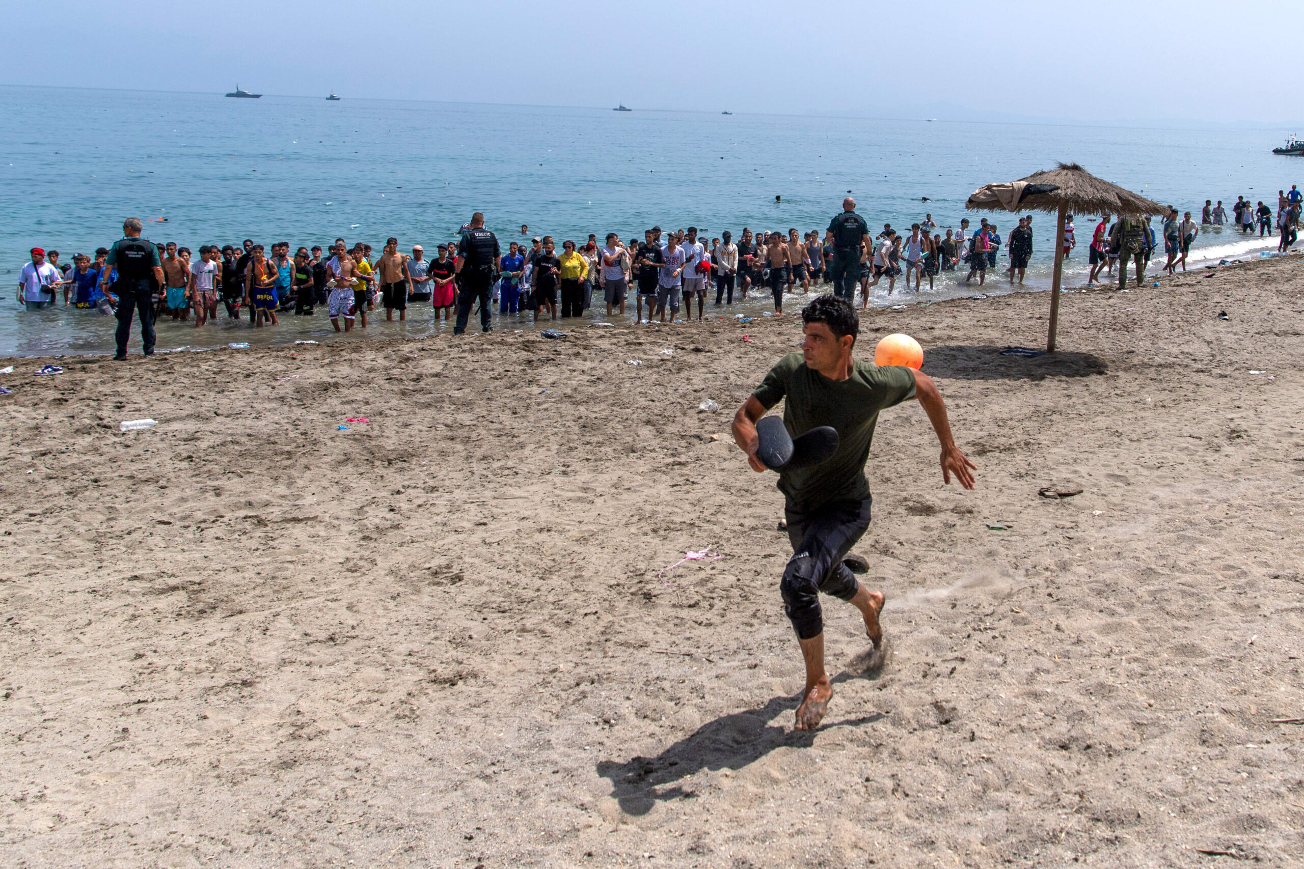 En la playa del Tarajal, un hombre se escapa del cordón policial que bloquea el acceso a la orilla, el viernes 31 de julio; en el tercer día de la crisis, la Guardia Civil concentra ahora a los recién llegados a la orilla. © AP Photo/Antonio Sempere/SIPA