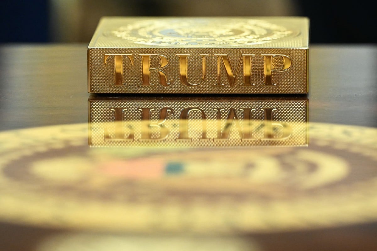 Un posavasos dorado con el sello presidencial y el apellido «TRUMP» grabados, colocado sobre una mesa del Despacho Oval, reflejándose en la superficie barnizada. Foto: Casa Blanca