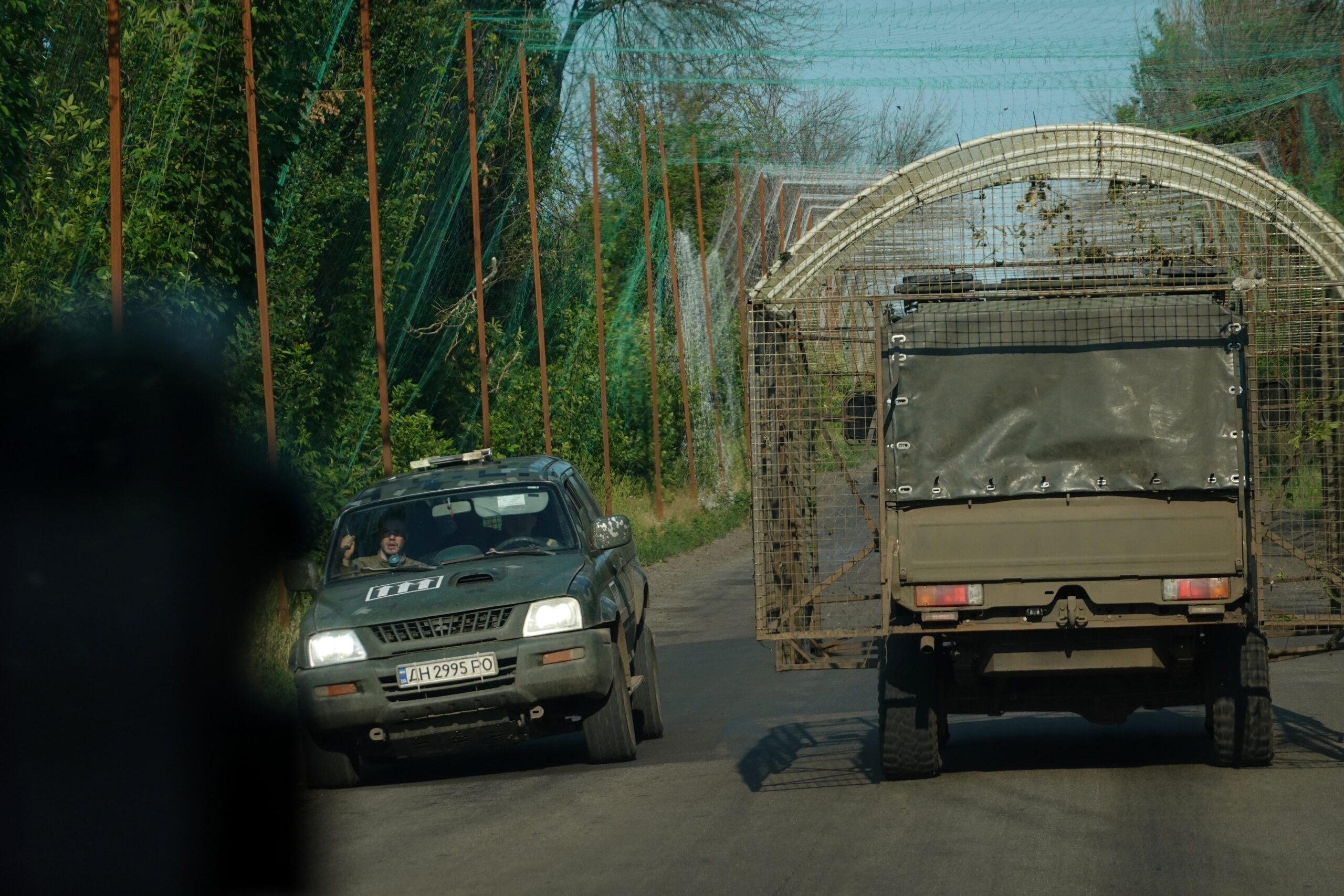 Dos vehículos militares, uno de ellos un camión equipado con una jaula antidrones, se cruzan bajo la cubierta de una red antidrones cerca de Kramatorsk, el 7 de julio de 2026.