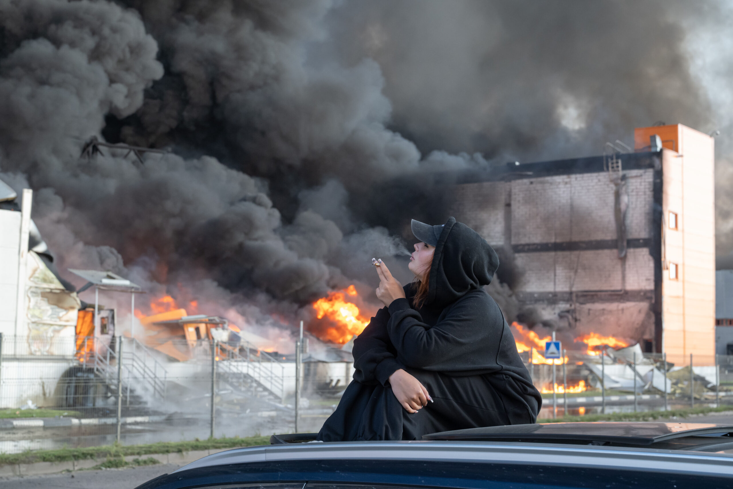 Una mujer fuma mientras observa un almacén en llamas en la zona de Utkina Zavod, cerca del pueblo de Novosaratovka. Foto: Stringer / SOPA Images/SIPA