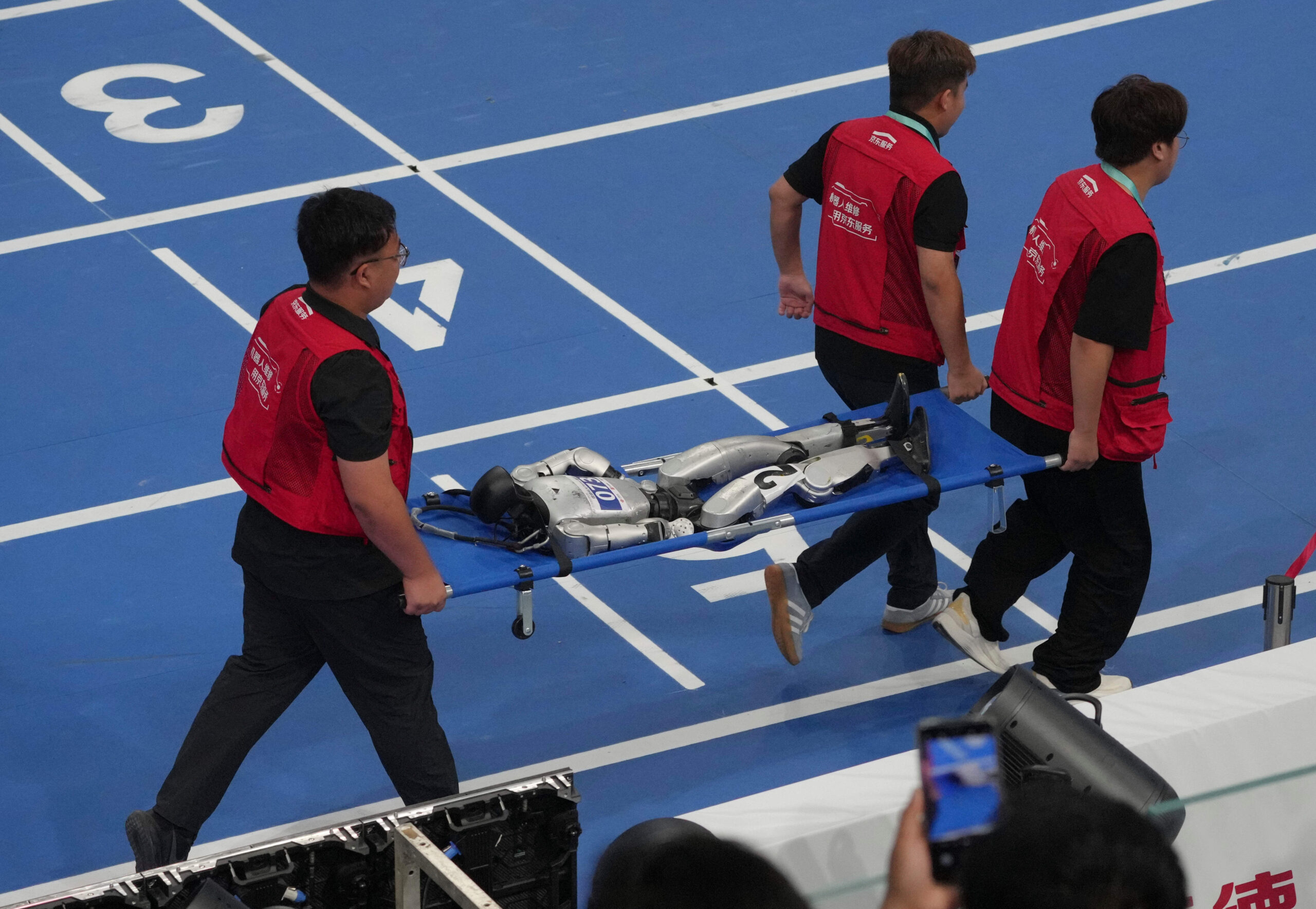 Un robot humanoide es retirado del recinto tras haber participado en la final de los 100 metros con obstáculos el 24 de agosto.