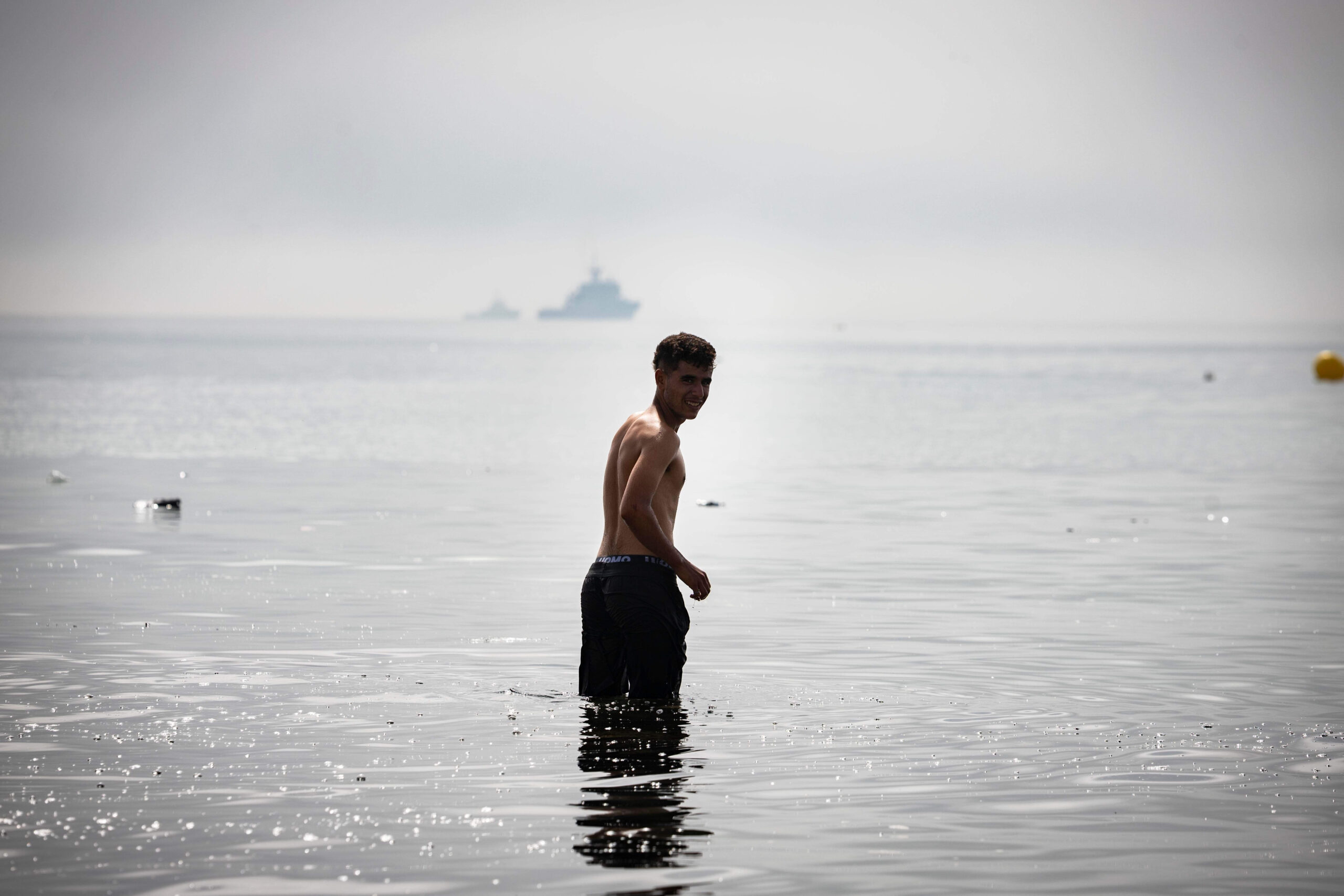 En la madrugada del 1 de agosto de 2026, un joven que se había quedado en Ceuta vuelve a Marruecos por el paso fronterizo del Tarajal, bajo la mirada de los barcos patrulleros. Foto: Samuel Vega