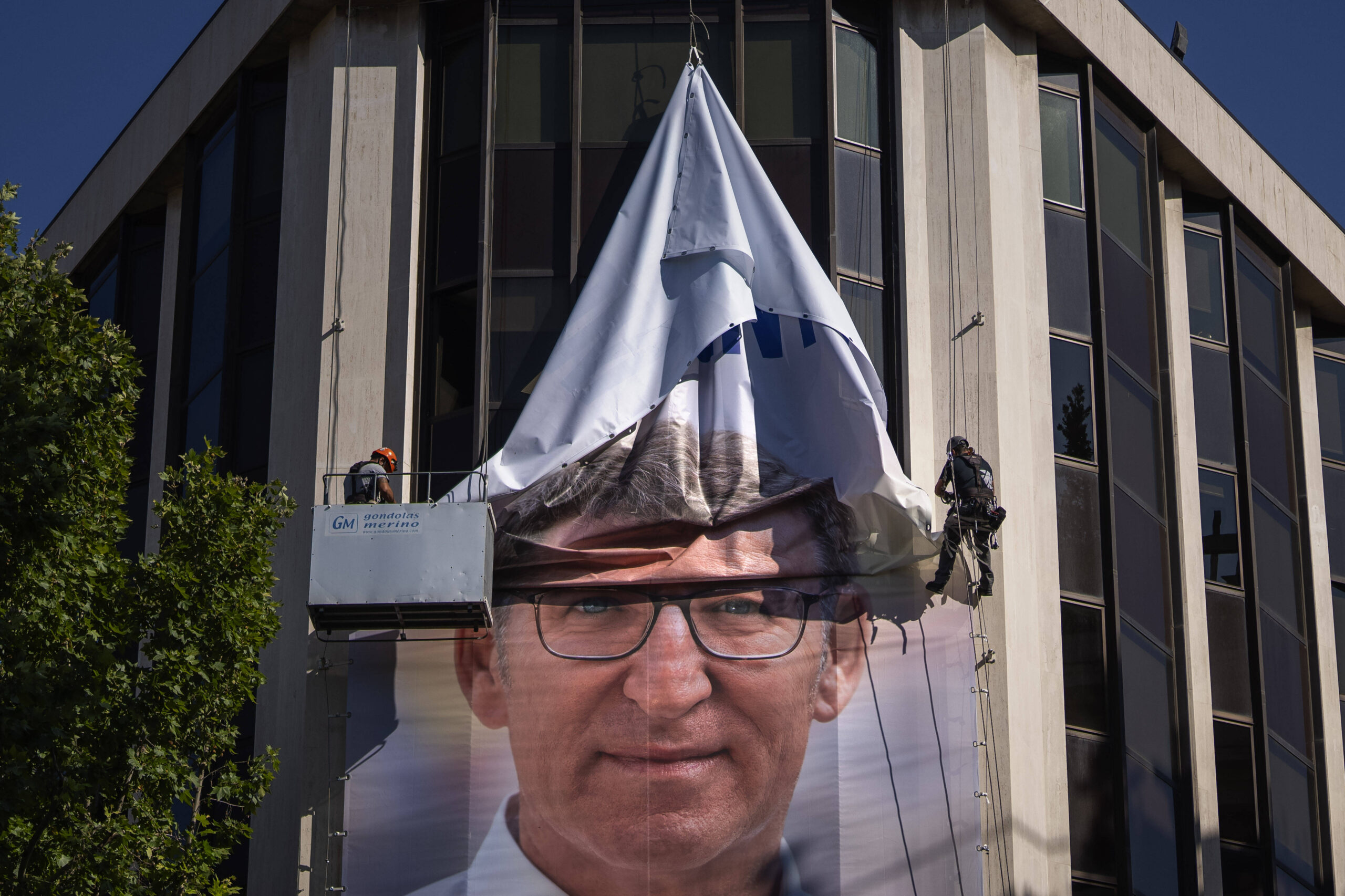 Trabajadores retiran un cartel electoral que muestra a Alberto Feijoo, líder del conservador Partido Popular, en la sede del partido en Madrid, España, el 24 de julio de 2023. © Emilio Morenatti/AP/SIPA