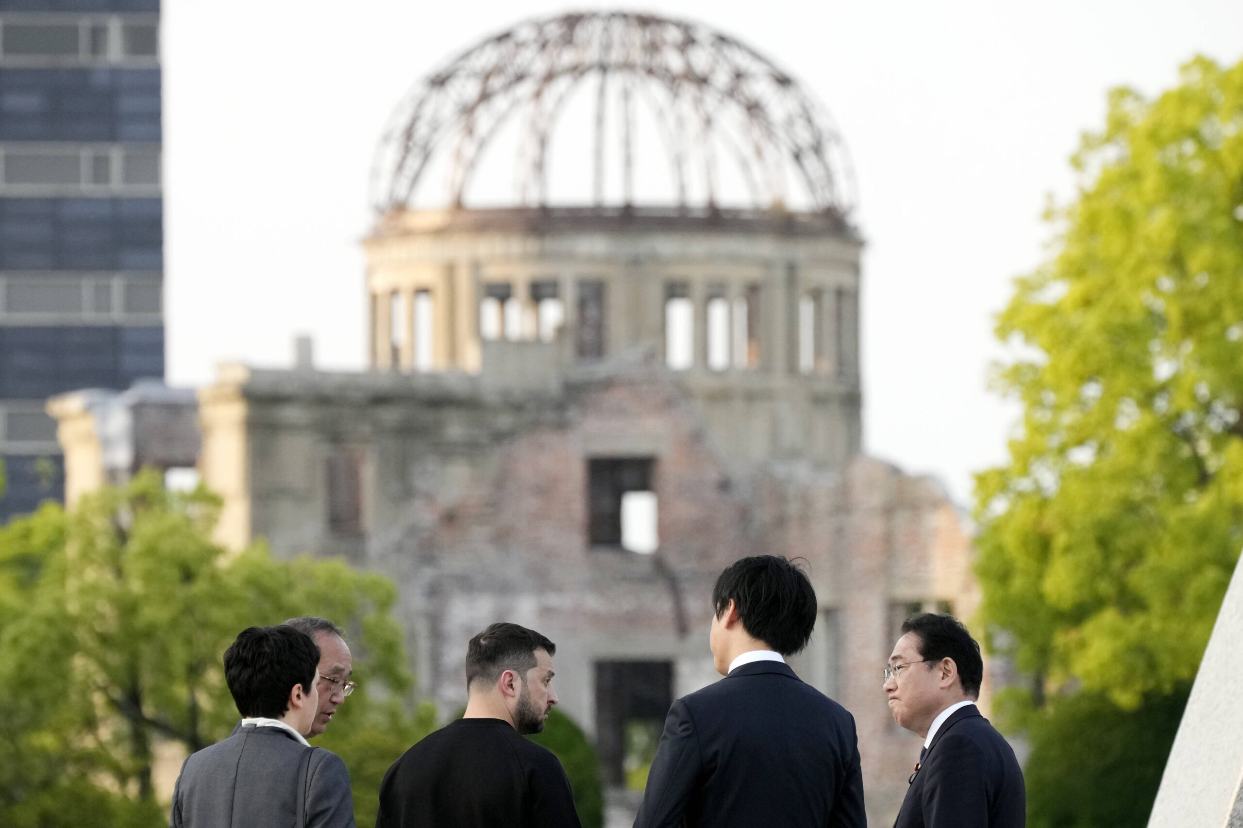 Le président ukrainien Volodymyr Zelenskyy et le premier ministre japonais Fumio Kishida discutent après avoir déposé des fleurs devant le cénotaphe des victimes de la bombe atomique dans le parc du mémorial de la paix d'Hiroshima, après avoir été invités au sommet du Groupe des sept (G7) à Hiroshima, dans l'ouest du Japon, le dimanche 21 mai 2023.© AP Photo/Eugene Hoshiko, Pool