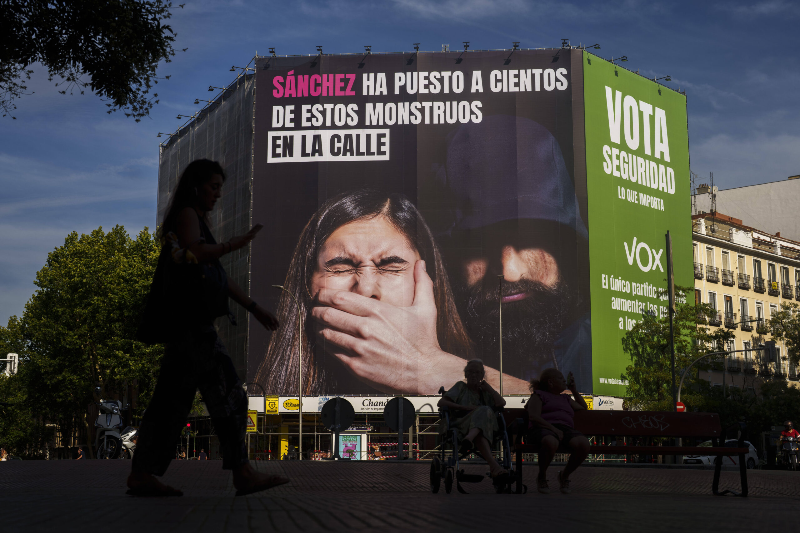 Une femme passe devant une affiche électorale géante du parti d'extrême droite VOX, sur laquelle on peut lire en espagnol : «Sanchez a mis des centaines de ces monstres dans la rue. Votez pour la sécurité. C'est ce qui compte.» © Manu Fernandez/AP/SIPA