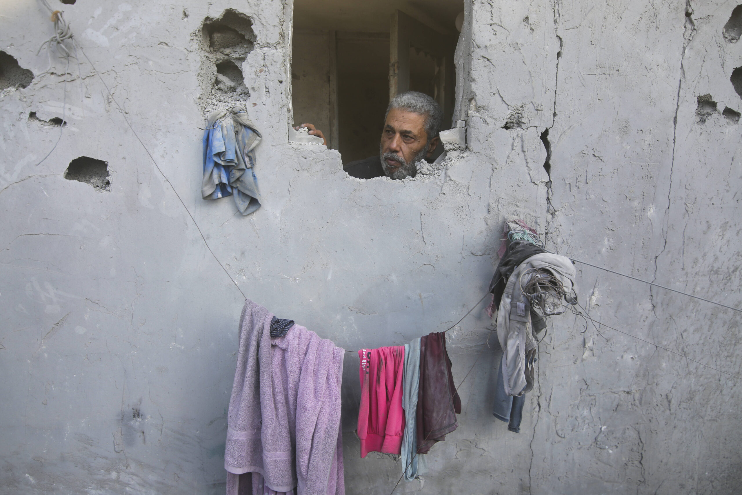 À Rafah, dans le Sud de la bande de Gaza, un homme regarde à travers le mur de sa maison abimé par une frappe israélienne. © Hatem Ali/AP/SIPA