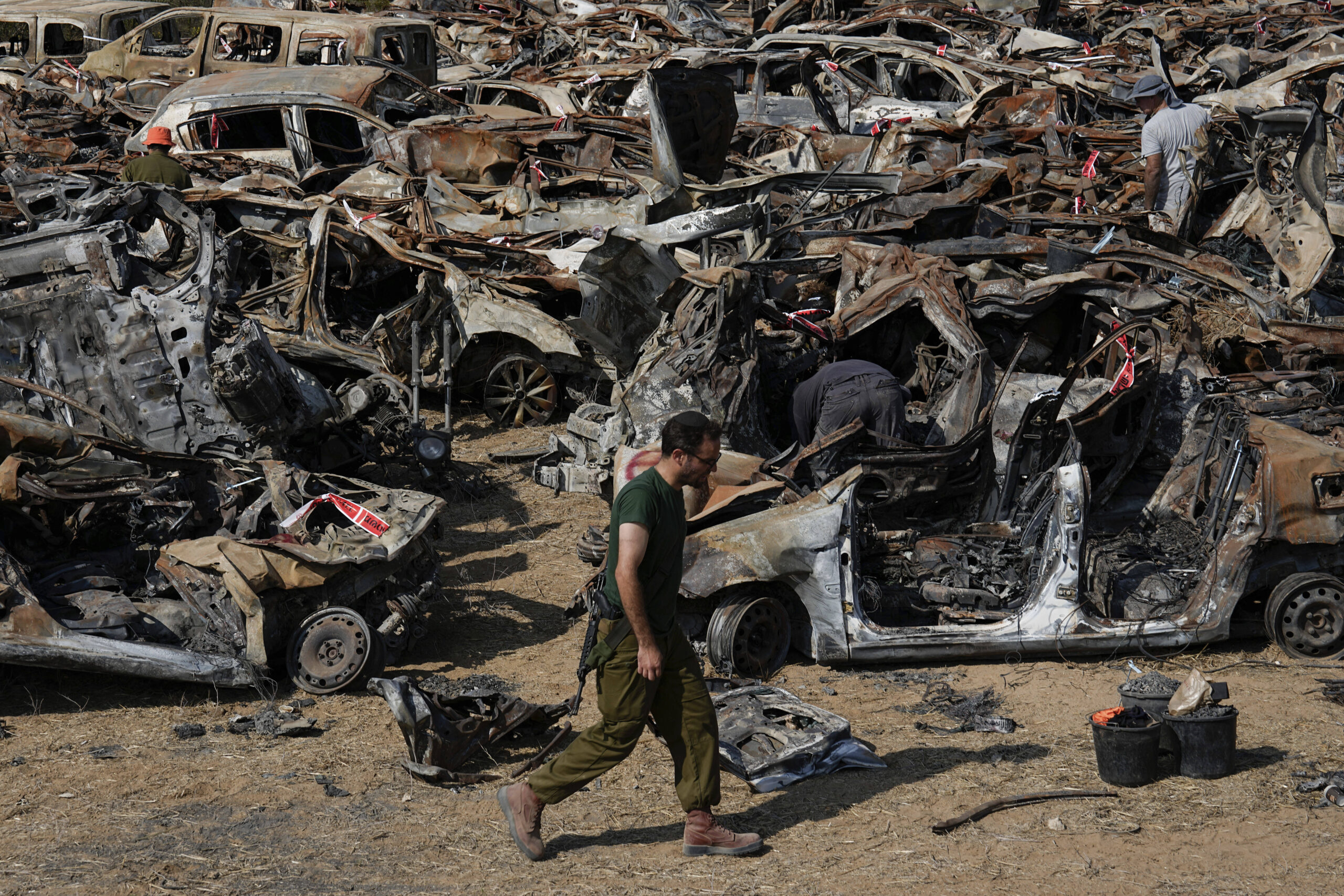 Les forces de sécurité israéliennes inspectent les véhicules calcinés lors de l'attaque transfrontalière sanglante du 7 octobre par des militants du Hamas, à l'extérieur de la ville de Netivot, dans le sud d'Israël. Les véhicules ont été rassemblés et placés dans une zone proche de la frontière de Gaza après l'attaque, qui a fait 1 200 morts et 240 otages. © AP Photo/Ariel Schalit
