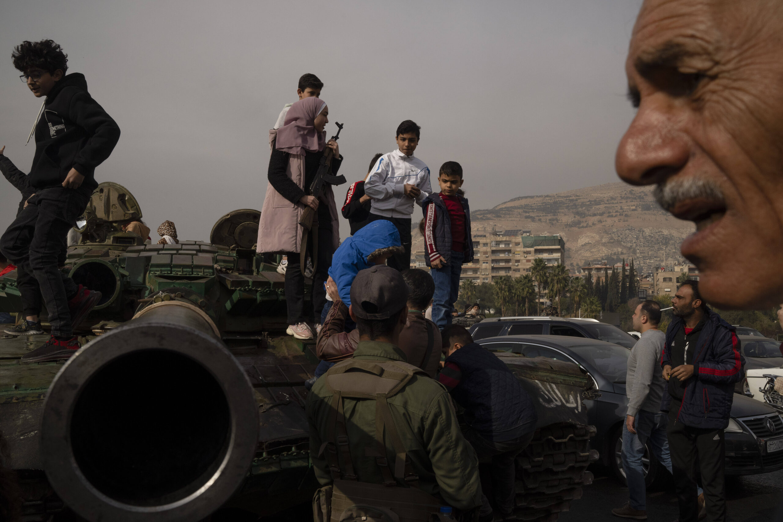 Un jeune, tenant un fusil emprunté à un combattant de l'opposition syrienne, pose pour une photo sur un char des forces gouvernementales qui a été laissé dans une rue, sur la place des Omeyyades à Damas, Syrie, mercredi 11 décembre 2024. © AP Photo/Leo Correa