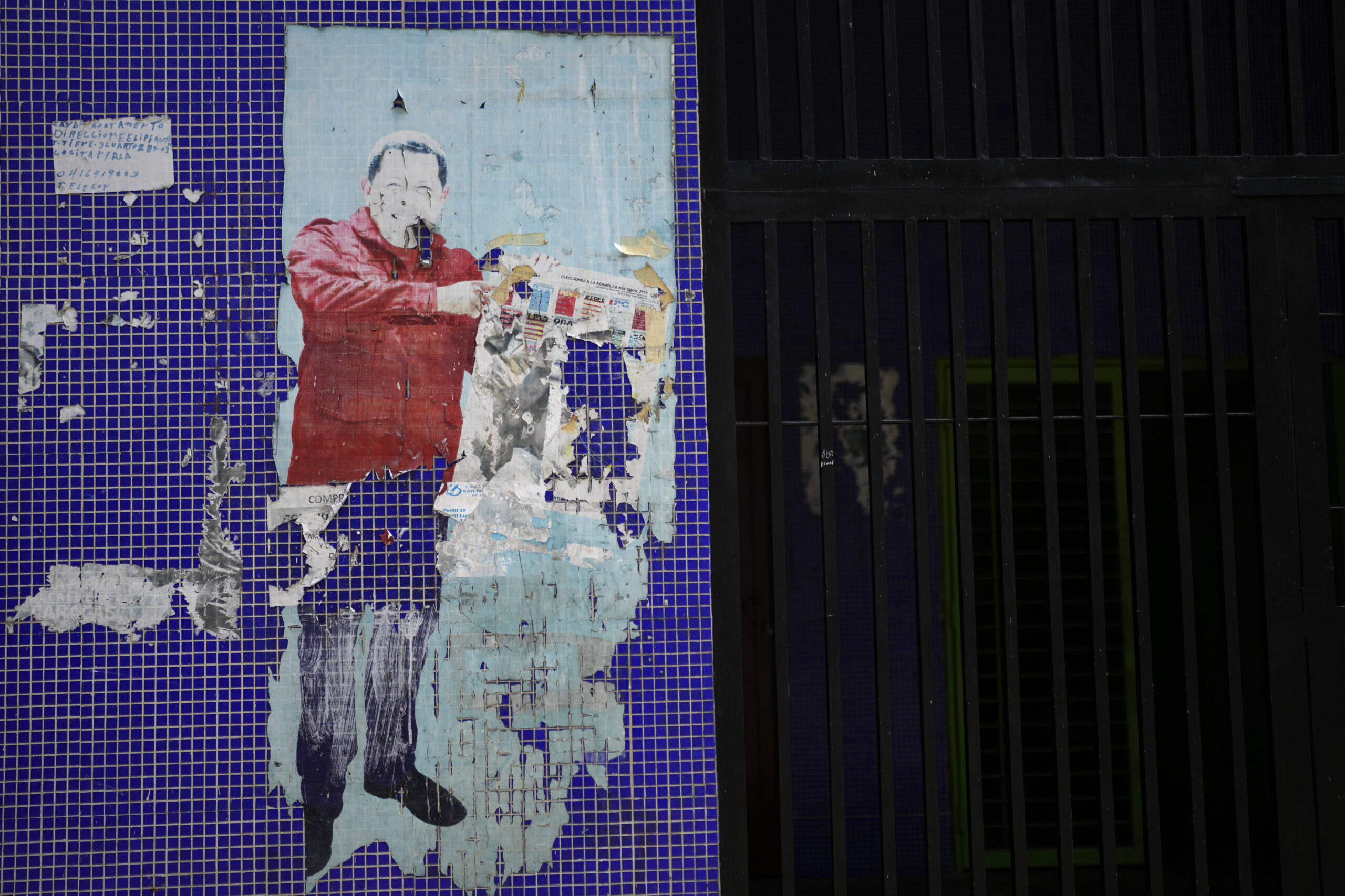 Une affiche décollée affichée sur un mur de carreaux montre une image du défunt président Hugo Chavez tenant un bulletin de vote, à Caracas, au Venezuela, le jeudi 21 mars 2024. © AP Photo/Ariana Cubillos