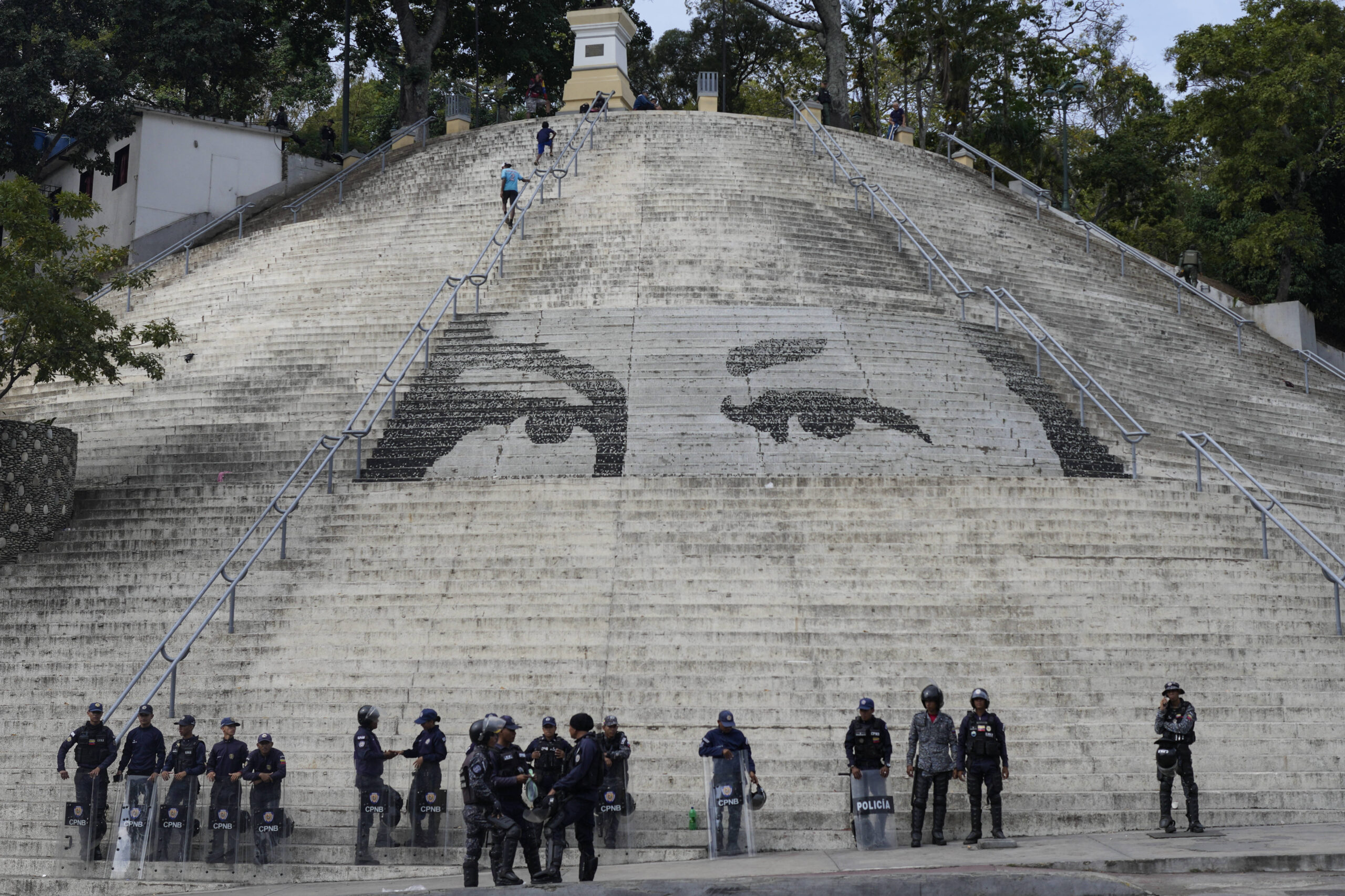 La police nationale bolivarienne monte la garde devant les marches présentant un graffiti géant des yeux du défunt président Hugo Chavez avant la prestation de serment du président Nicolas Maduro pour un troisième mandat, à Caracas, au Venezuela, dimanche 5 janvier 2025. © AP Photo/Matias Delacroix