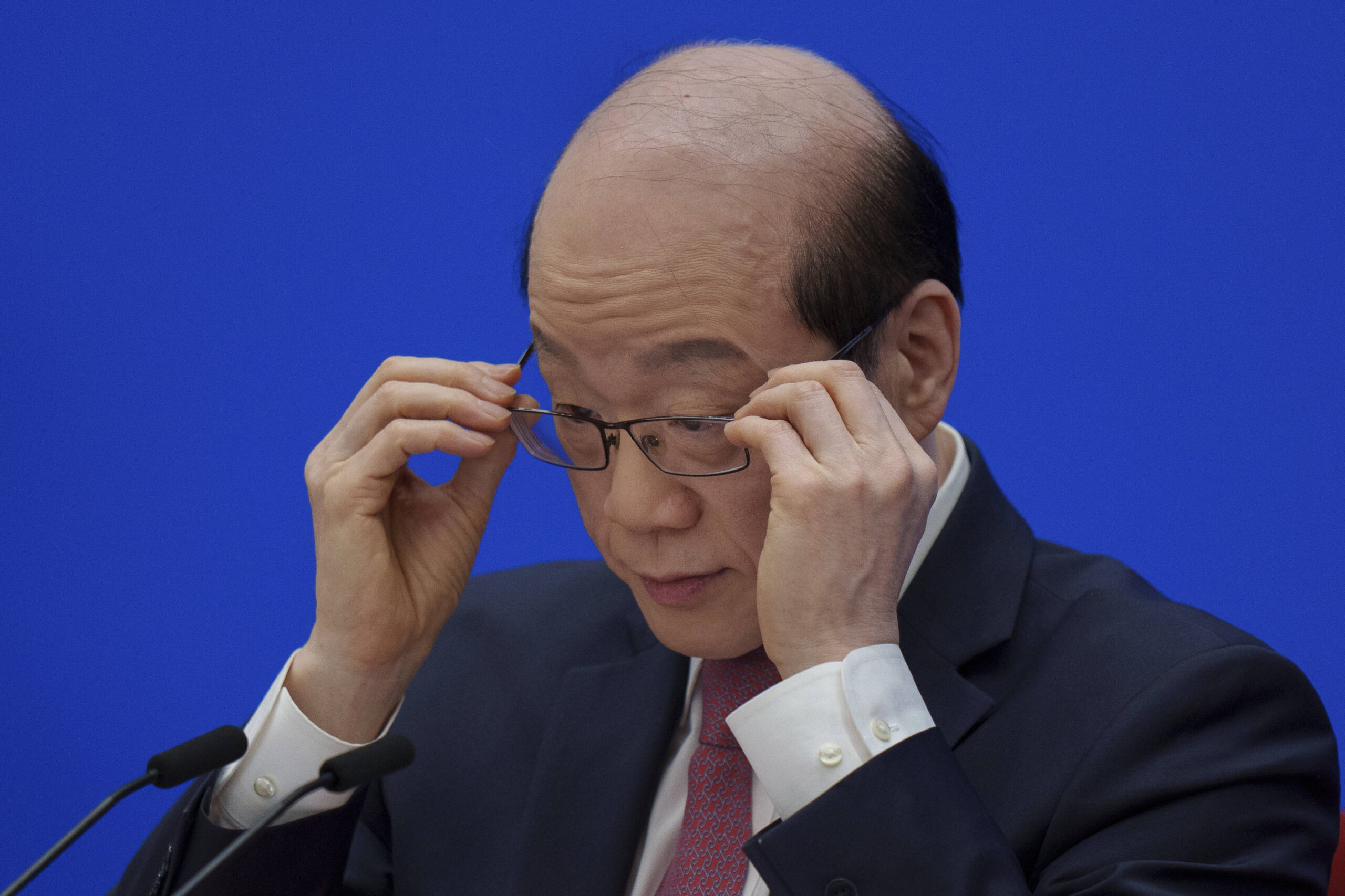 Liu Jieyi, porte-parole du principal organe consultatif politique chinois, ajuste ses lunettes lors d'une conférence de presse précédant l'ouverture de la Conférence consultative politique du peuple chinois au Grand Palais du Peuple à Pékin, en Chine, le lundi 3 mars 2025. © AP Photo/Vincent Thian
