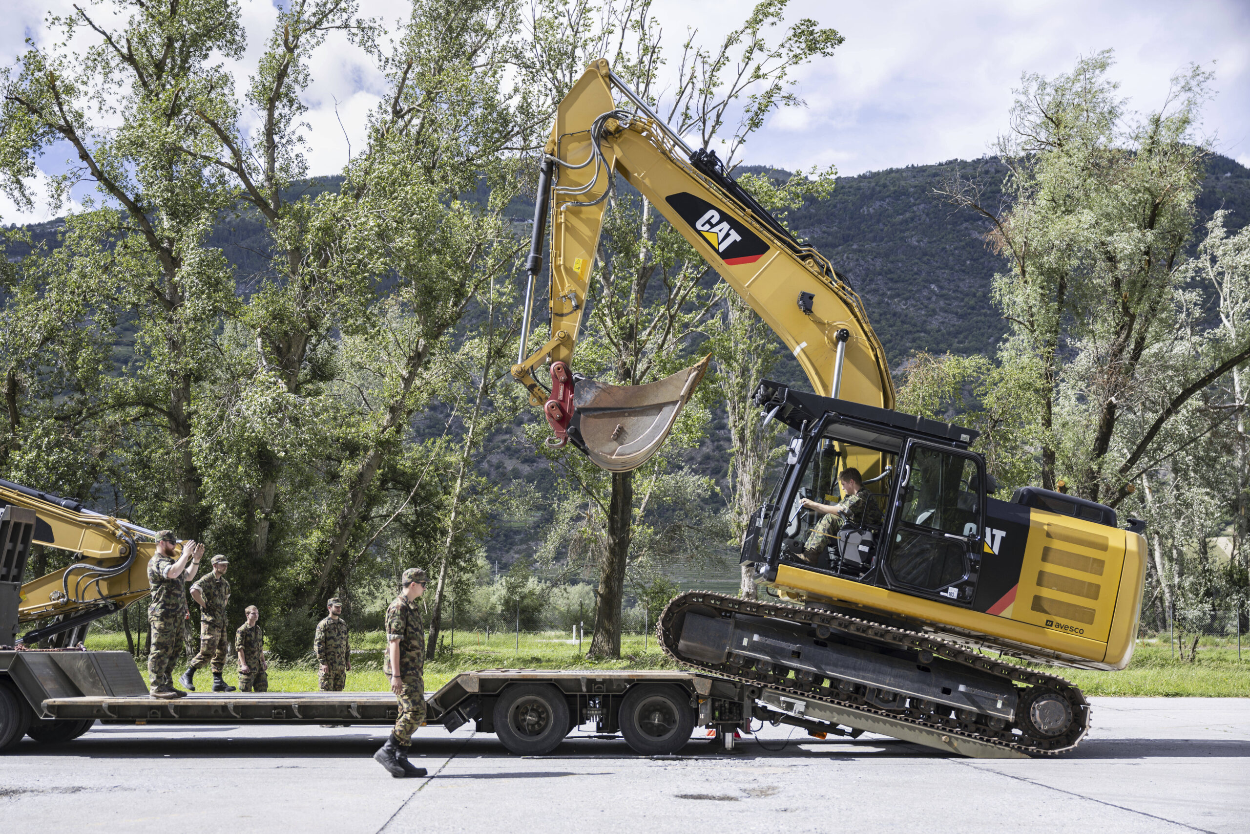 Des soldats de l'unité de secours en cas de catastrophe (Kata Hi Ber Bat) de l'armée suisse chargent des engins lourds sur des remorques afin de venir en aide au site de la coulée de boue catastrophique qui a causé d'importants dégâts dans le village de Blatten, sur la base militaire de Turtmann, en Suisse, le jeudi 29 mai 2025. © Alessandro della Valle/Keystone via AP
