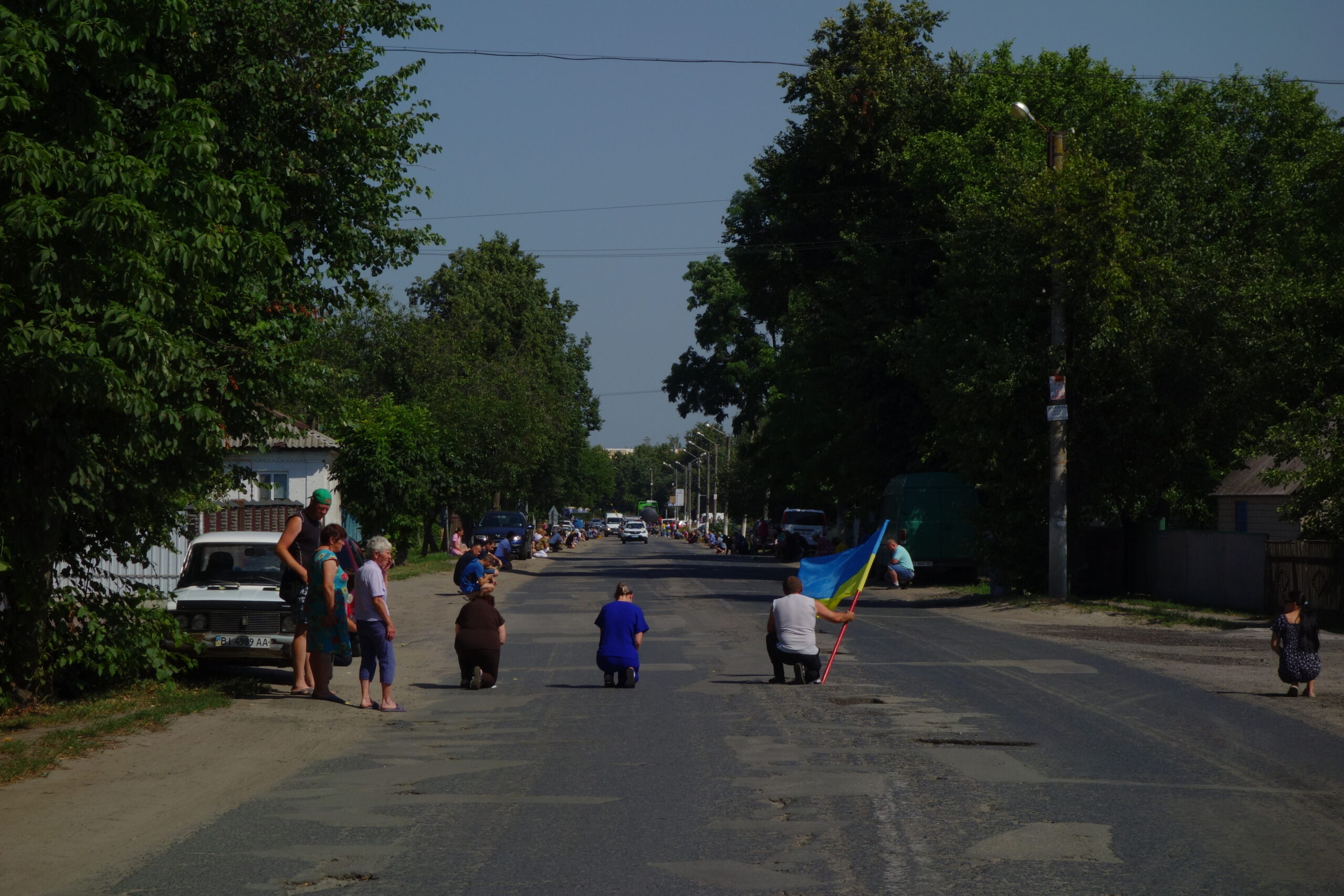 Des habitants de Kotelva, dans la région de Poltava, s'agenouillent le 10 juillet 2025 lors du passage du convoi funéraire d'un soldat tué au combat.