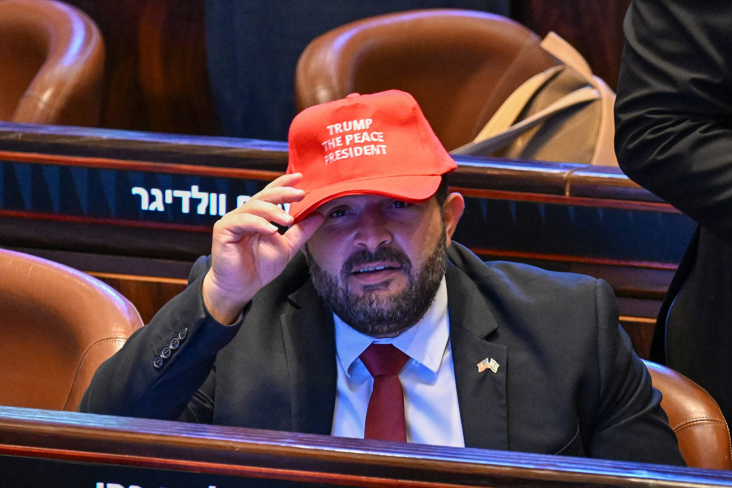 Des personnes portant des casquettes sur lesquelles on peut lire «TRUMP THE PEACE PRESIDENT» (Trump, le président de la paix) à l'intérieur de la Knesset, alors que le président Donald Trump s'apprête à prononcer un discours, le lundi 13 octobre 2025, à Jérusalem. © Kenny Holston/The New York Times via AP