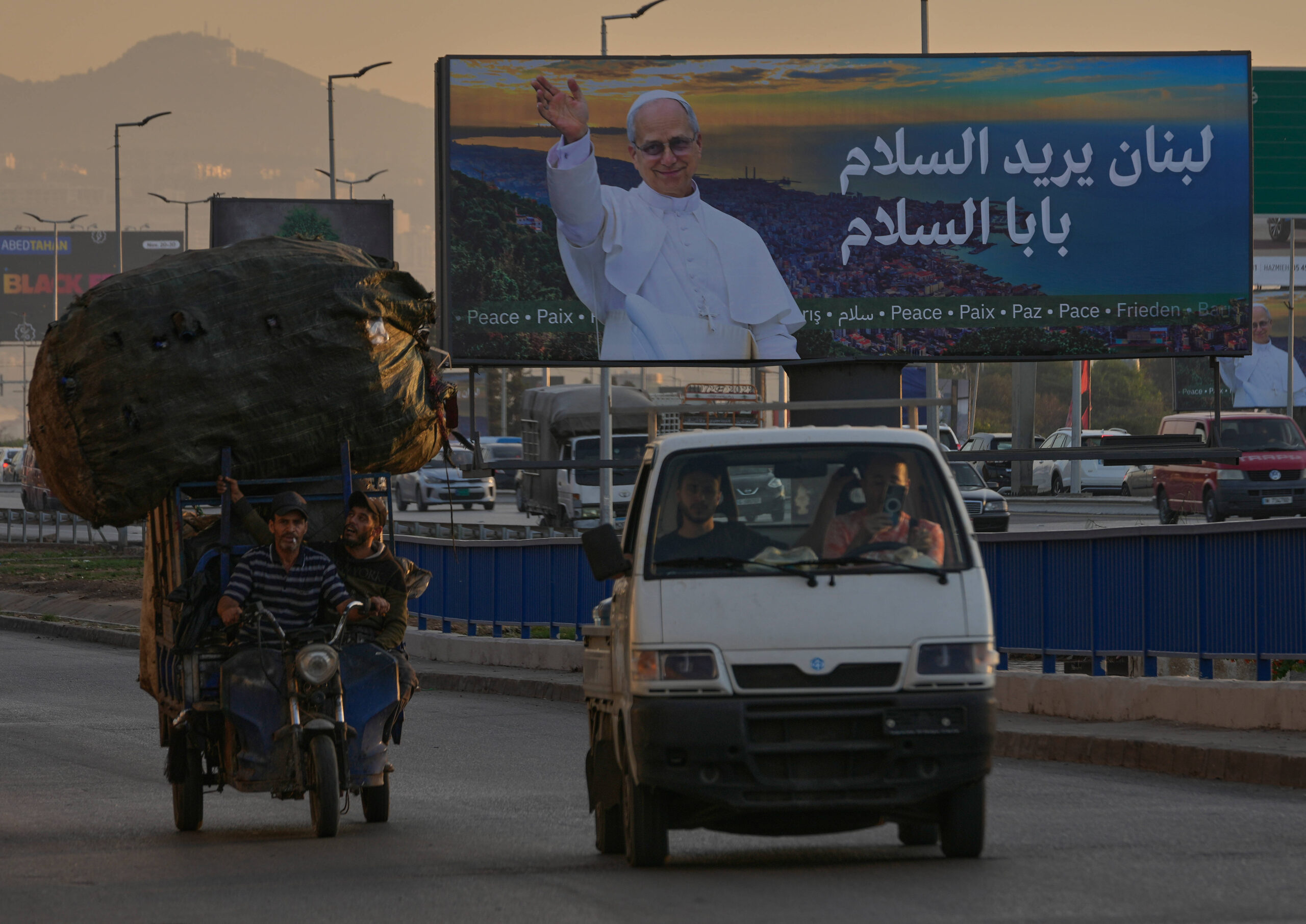 Sur une autoroute de Beyrouth, le vendredi 21 novembre 2025, une affiche montre une image du pape Léon XIV avant sa prochaine visite au Liban. Les mots en arabe signifient : «Le Liban a besoin de la paix, le pape de la paix.» © AP Photo/Hussein Malla