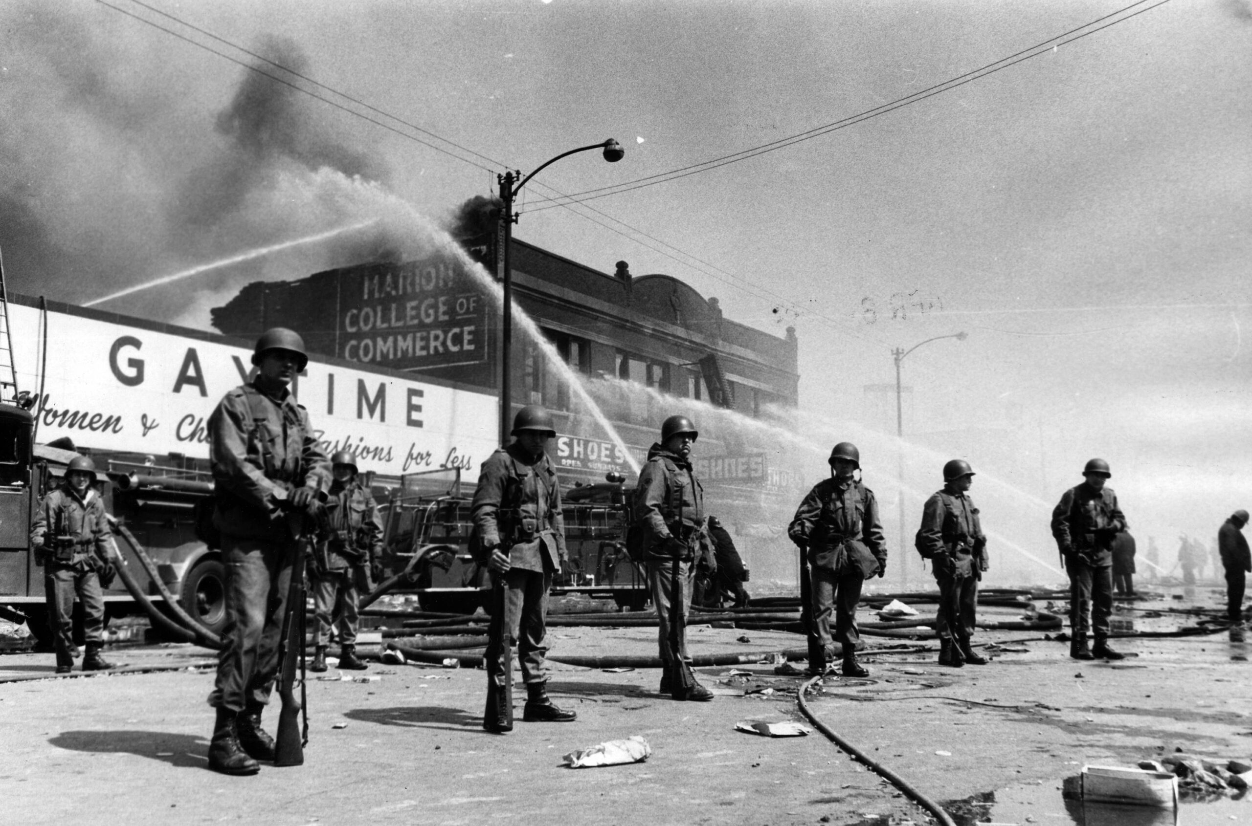 Des membres de la Garde nationale de l’Illinois observent les pompiers tenter de maîtriser un incendie dans le bloc 3200 de West Madison Street, le 6 avril 1968 à Chicago, au cœur des violences qui secouent alors la ville. © William Kelly