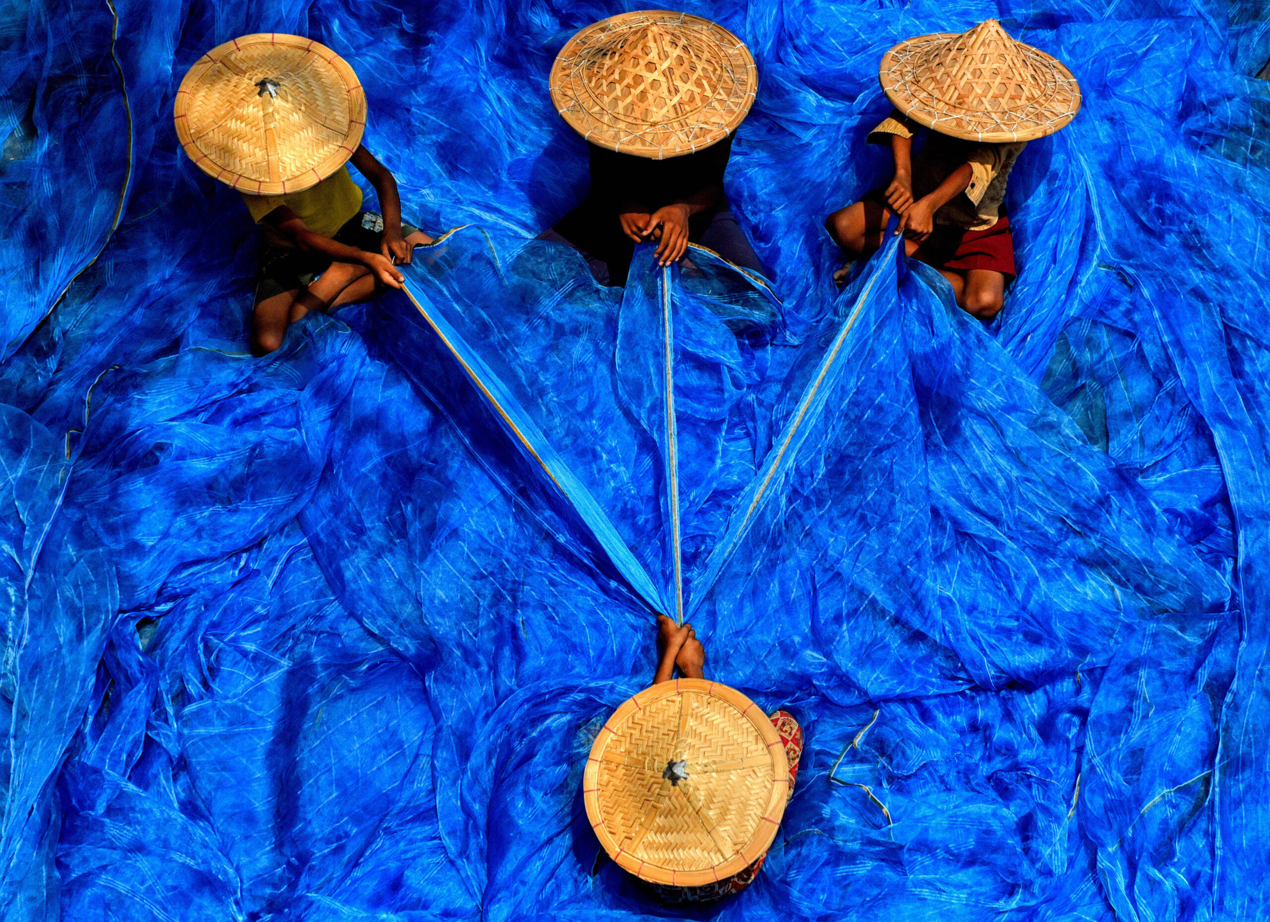 Des pêcheurs triant des filets de pêche bleus dans la région de Canning, en Inde, en mai 2023. © SOPA Images/SIPA