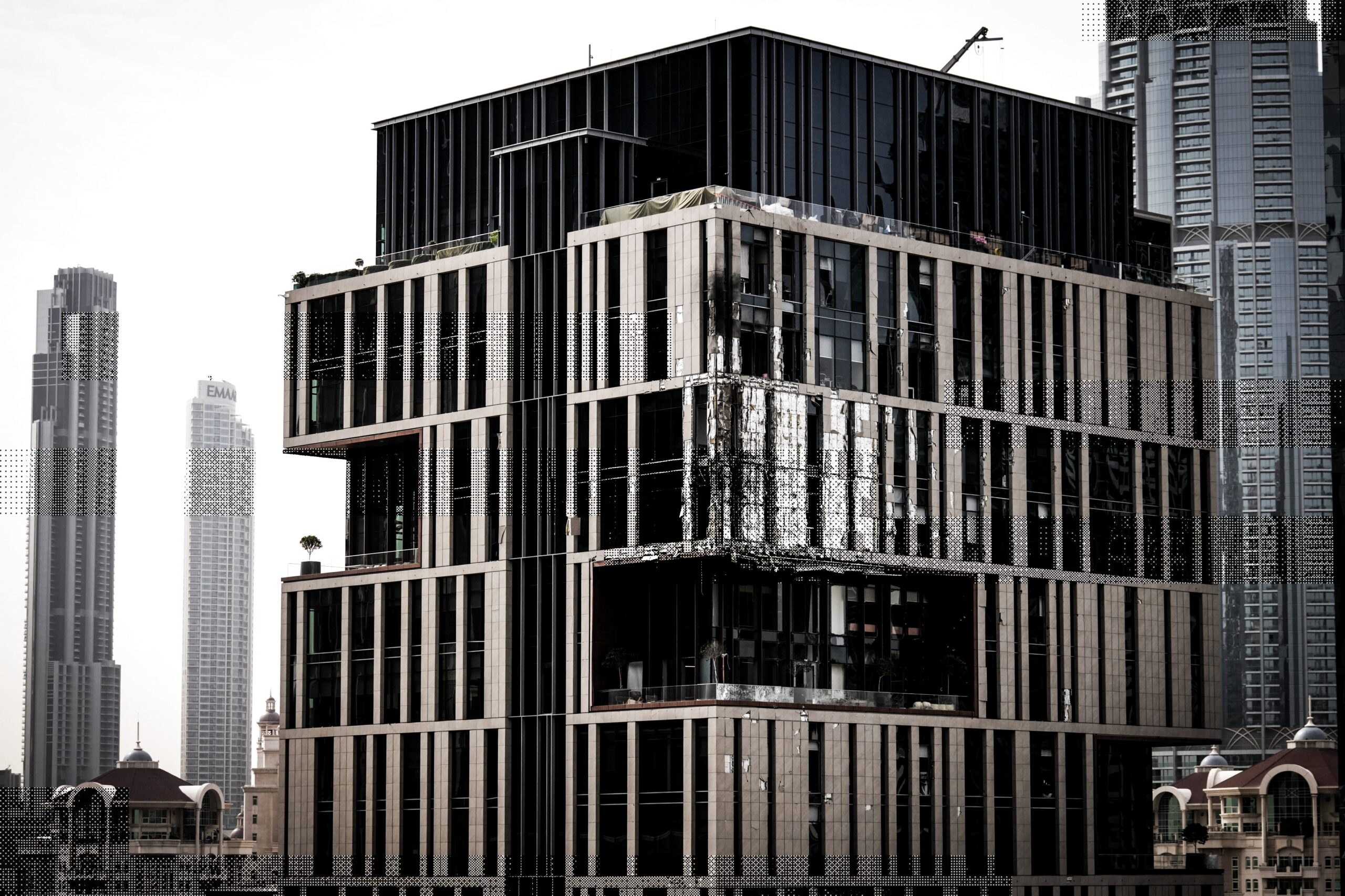 La façade d'un immeuble du quartier financier de Dubaï apparaît partiellement endommagée. Selon les autorités, ces dégâts ont été causés par la chute de débris à la suite d'une interception réussie, aux Émirats arabes unis, vendredi 13 mars 2026. © AP Photo/Altaf Qadri