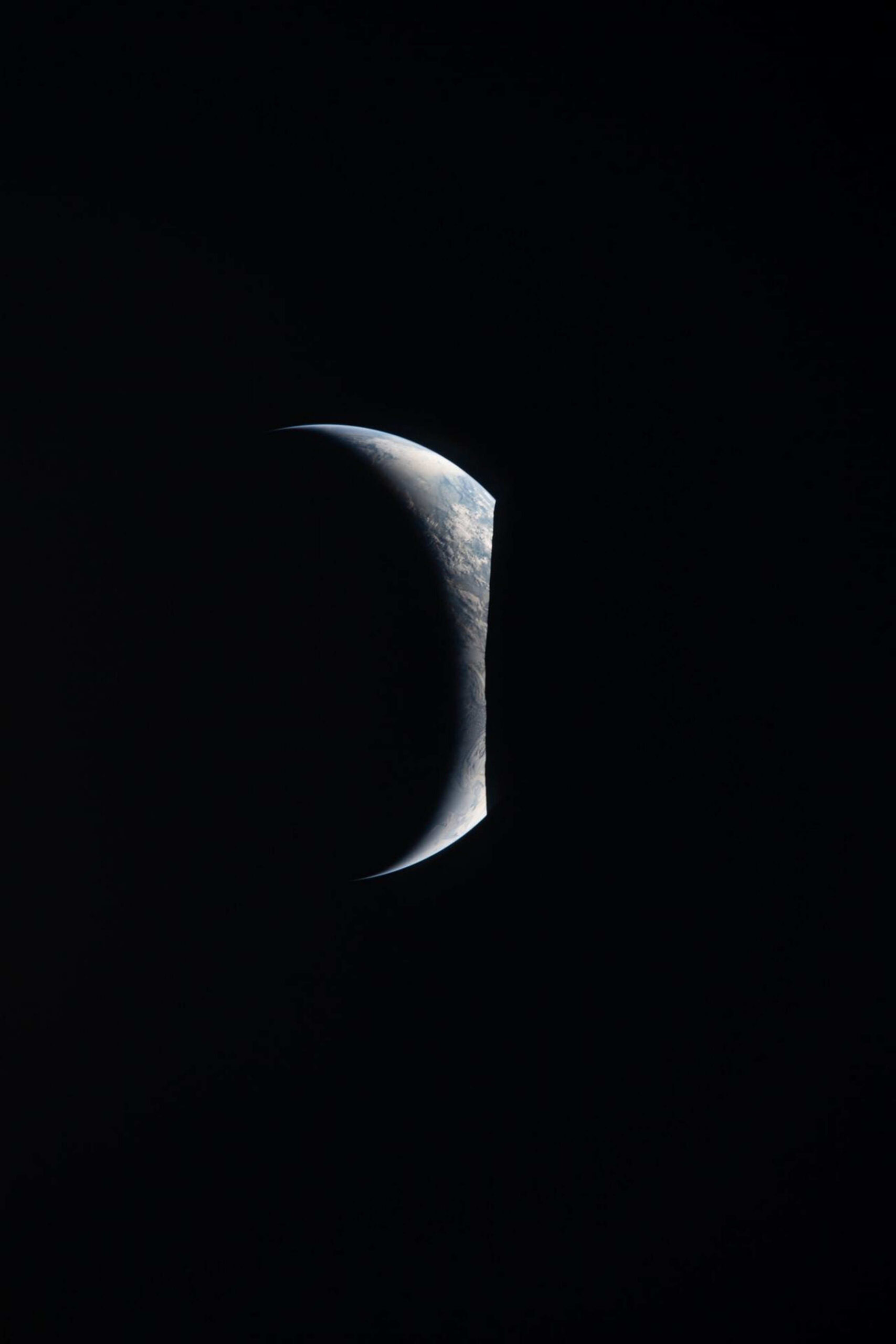 La Terre photographiée depuis le hublot du vaisseau spatial Orion à 19 h 22 (heure de l'Est) lors du survol de la face cachée de la Lune par l'équipage d'Artemis II le 7 avril 2026. La Terre apparaît sous la forme d'un croissant délicat, dont seule la partie supérieure est éclairée. La teinte bleue de la planète et les systèmes de nuages blancs épars se détachent sur la noirceur de l'espace, tandis que la partie inférieure s'estompe dans la nuit. Prise avec un objectif de 400 mm, l'image, intitulée «Earthrise», révèle un alignement saisissant entre la Terre et la Lune.© NASA/UPI, Shutterstock.