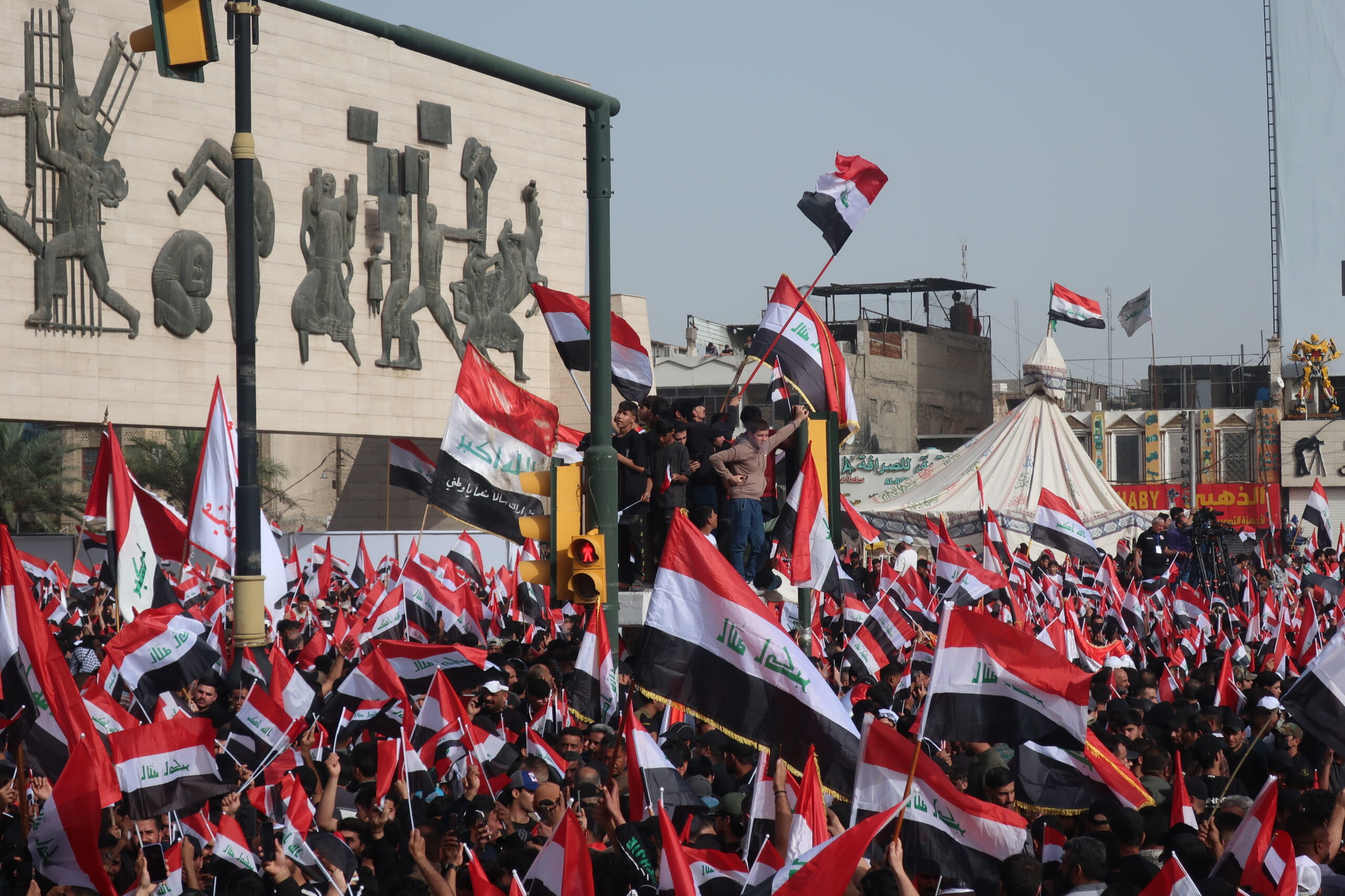 Des manifestants sadristes se hissent en hauteur pour former une colonne le 4 avril 2026 sur la place Tahrir de Bagdad, lieu habituel des protestations irakiennes. © Nicolò Sancassiani