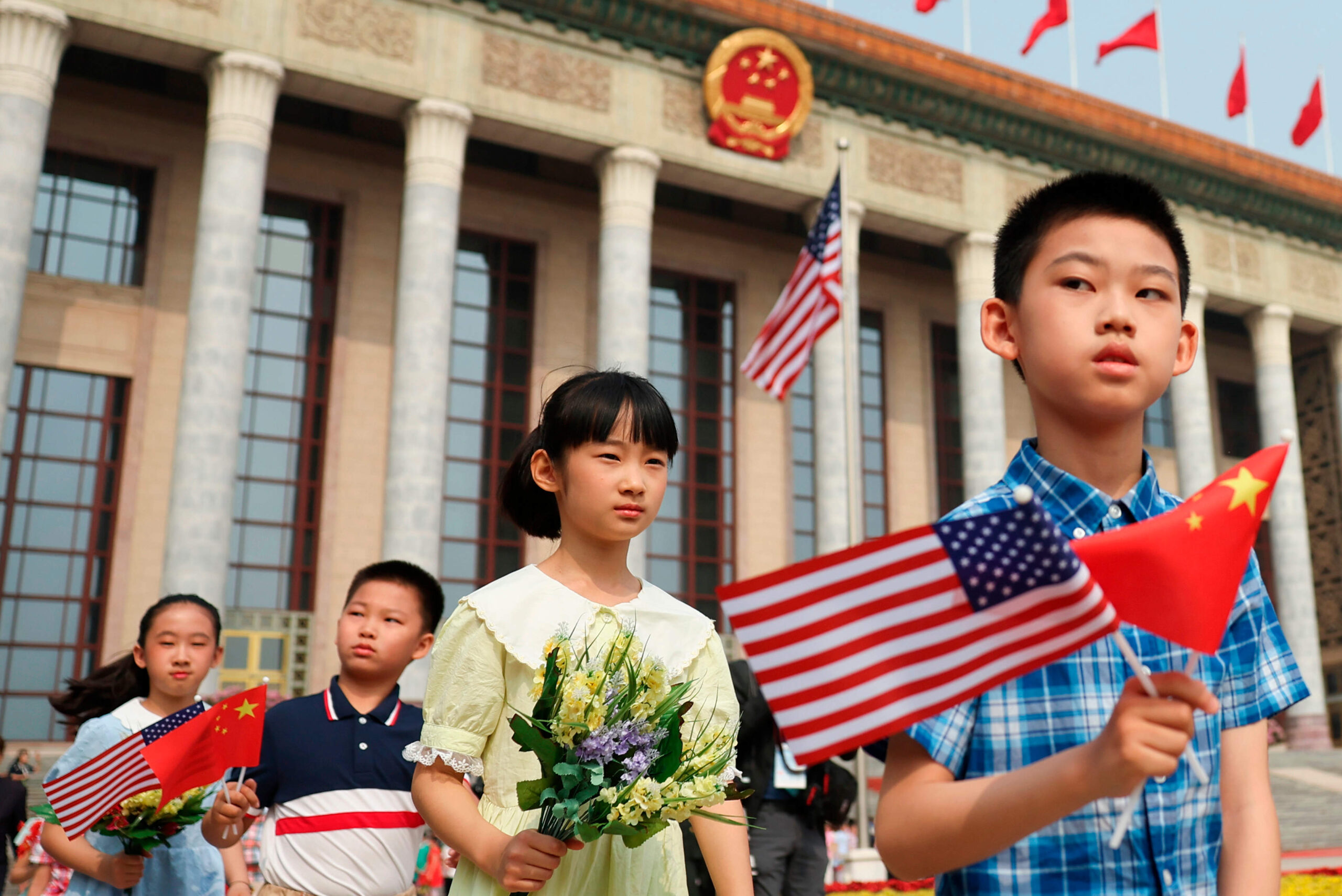 Des enfants brandissent des drapeaux chinois et américains avant la cérémonie d'accueil du président américain Donald Trump par le président chinois Xi Jinping au Grand Hall du Peuple à Pékin, le jeudi 14 mai 2026. © Maxim Shemetov/Pool Photo via AP