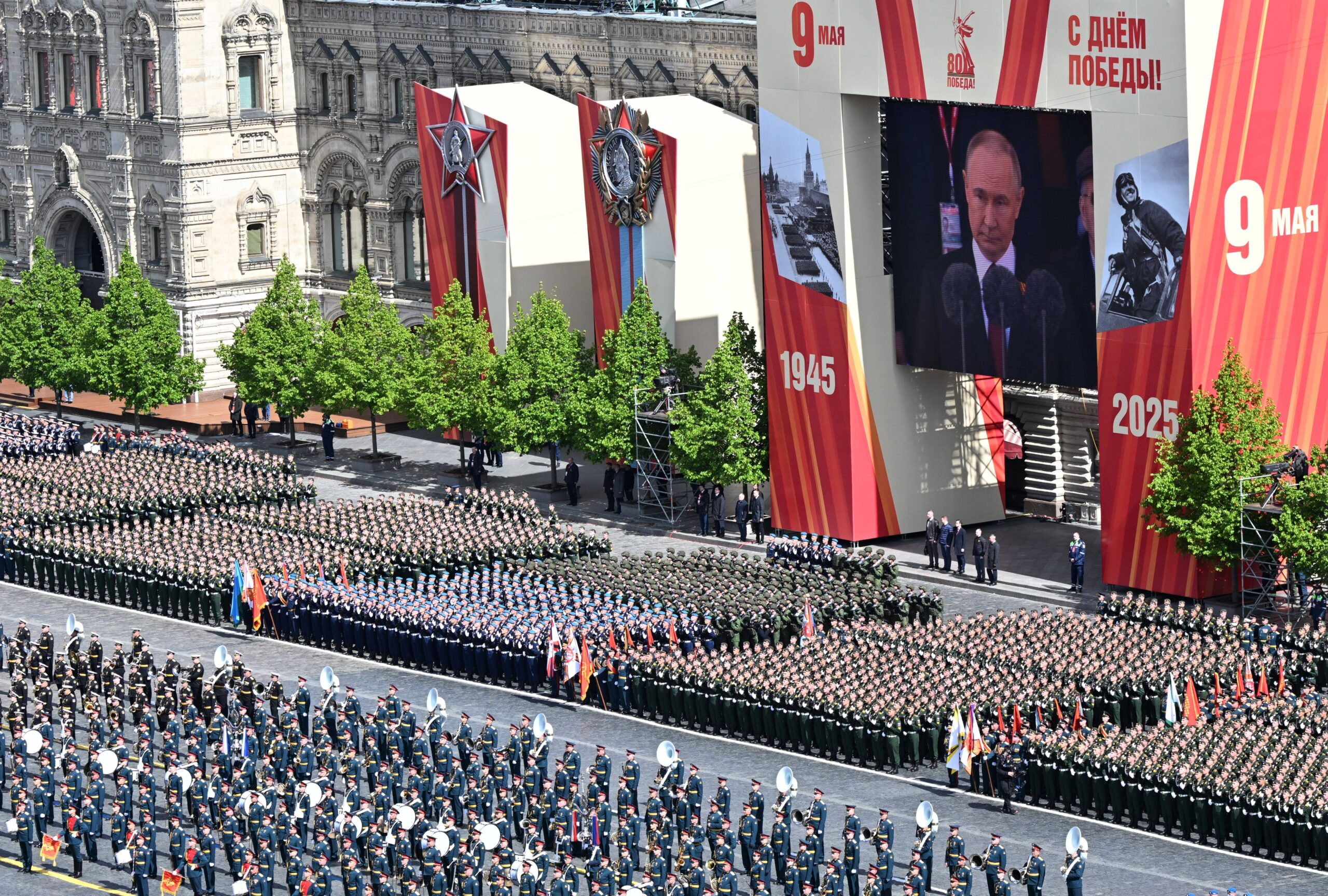 Dans une scénographie qui sature l'espace, des milliers d'hommes sont figés sur la Place Rouge au garde-à-vous sous la vidéo géante retransmettant en direct le discours de Vladimir Poutine, encadré par les dates 1945-2025. Photo : Maksim Bogodvid / RIA Novosti