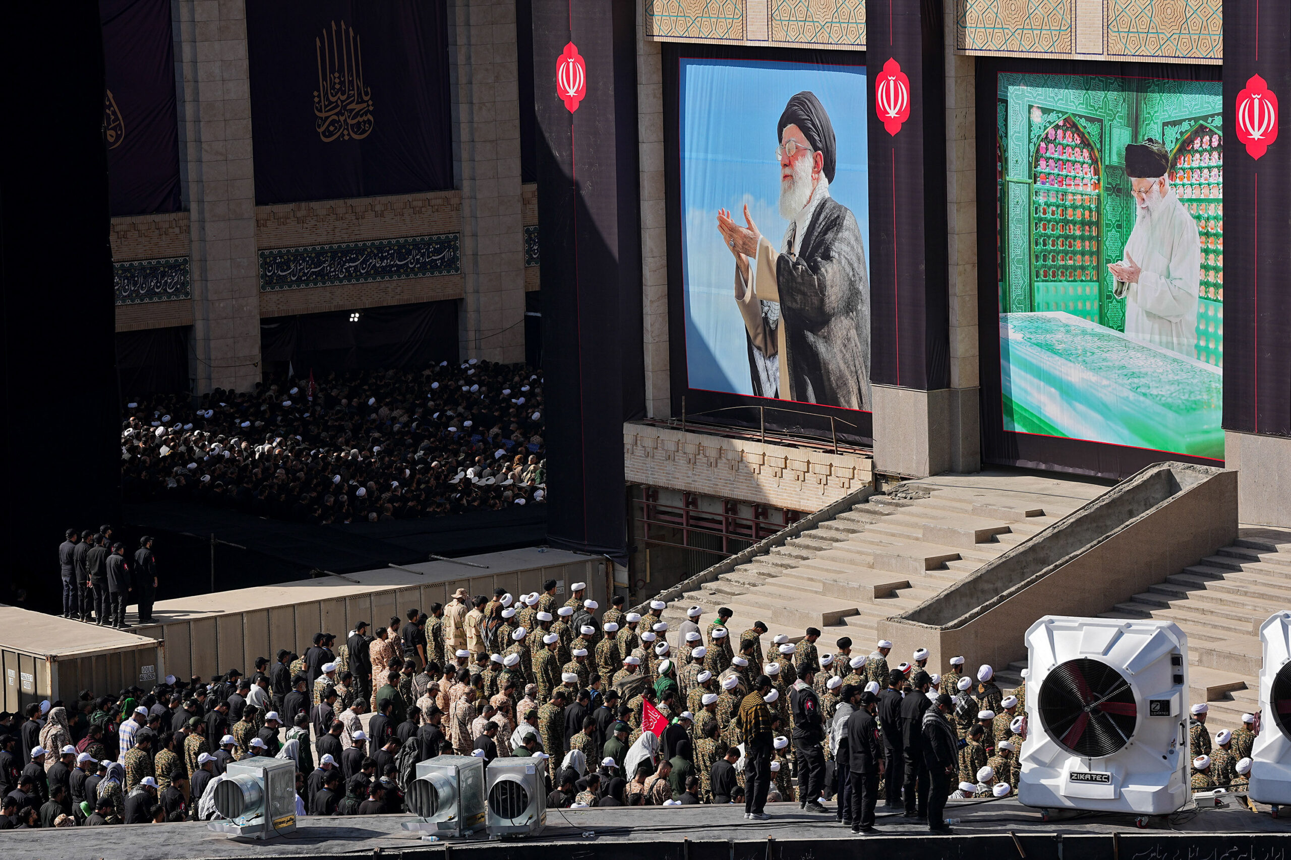 Des religieux et des militaires iraniens prient devant les images du Guide projetées sur de grands écrans à la Grande Mosquée Mosalla, le 5 juillet 2026. © Hamed Malekpour/MEI/Sipa