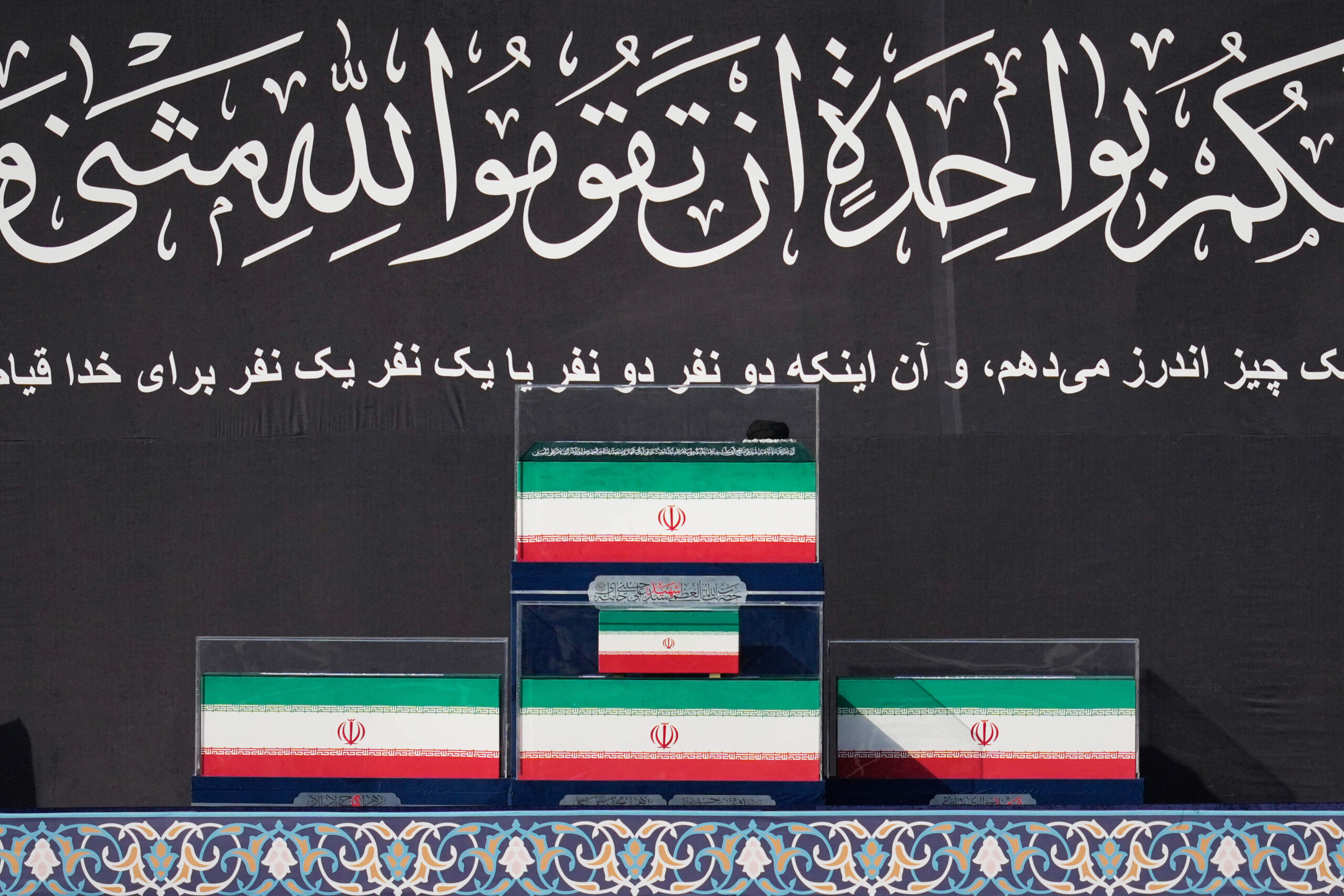 Les cercueils du défunt guide suprême iranien et de ses proches sont exposés sur une estrade au début des funérailles, à la mosquée Imam Khomeini de Téhéran, le samedi 4 juillet 2026. © AP/Altaf Qadri