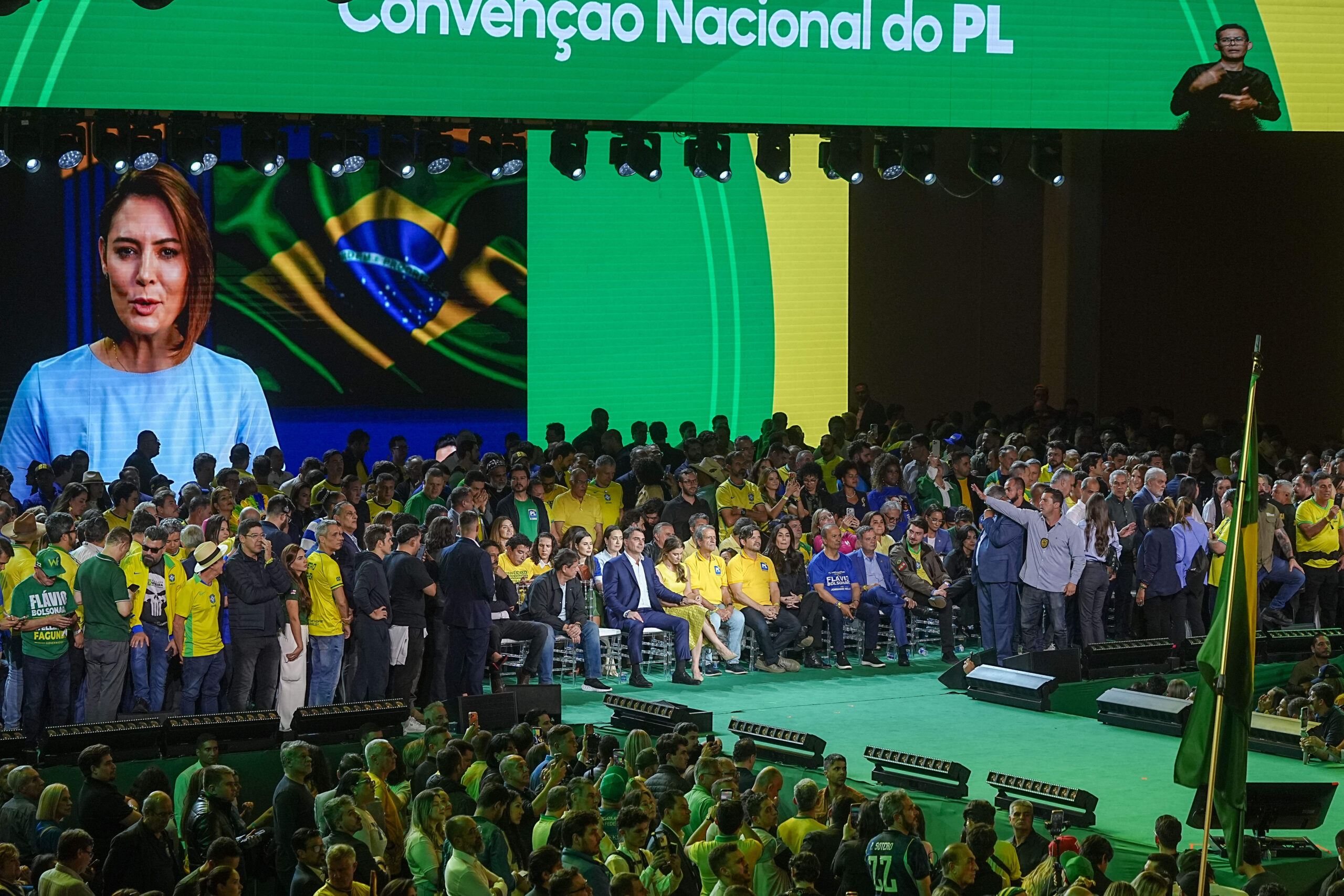 Michelle Bolsonaro s'adresse à la convention du PL par message vidéo. Figure du monde évangélique, l'ancienne première dame complète une mise en scène familiale faite d'absences : le père recréé par l'IA, l'épouse en visioconférence, et sur scène le fils investi.