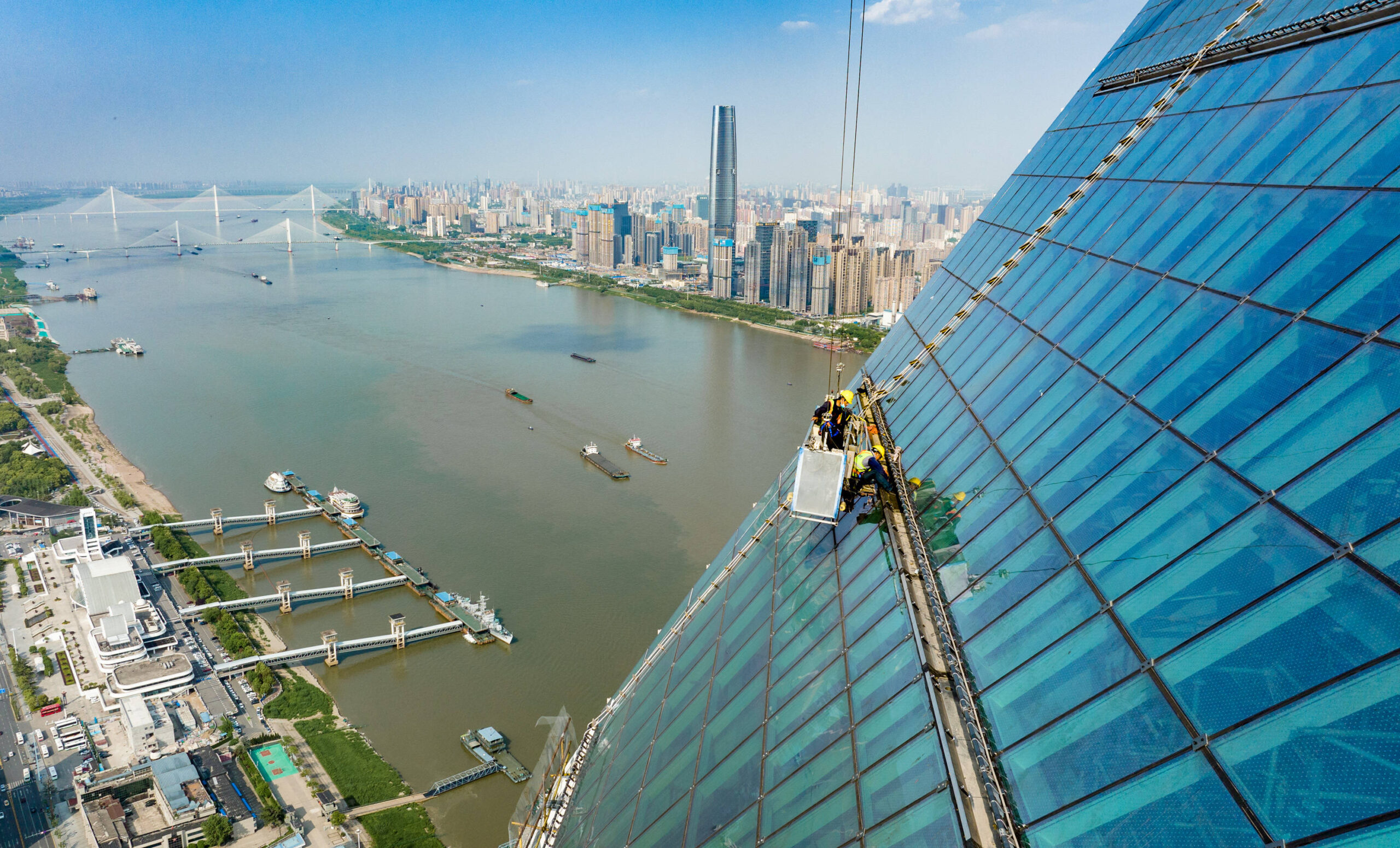 Des ouvriers se déplacent dans une nacelle suspendue à plus de 300 mètres afin d’achever la construction de la façade en verre du bâtiment, le 19 avril 2022.