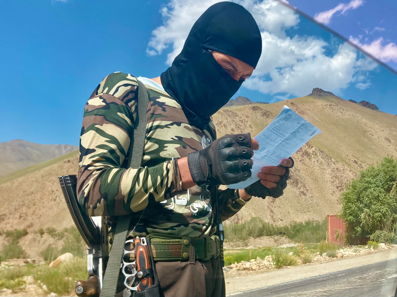 Un combattant taliban cagoulé vérifie un document à un poste de contrôle. Depuis 2021, les pots-de-vin qui accompagnaient chaque passage sous la République ont reculé. © Nicolò Sancassiani.