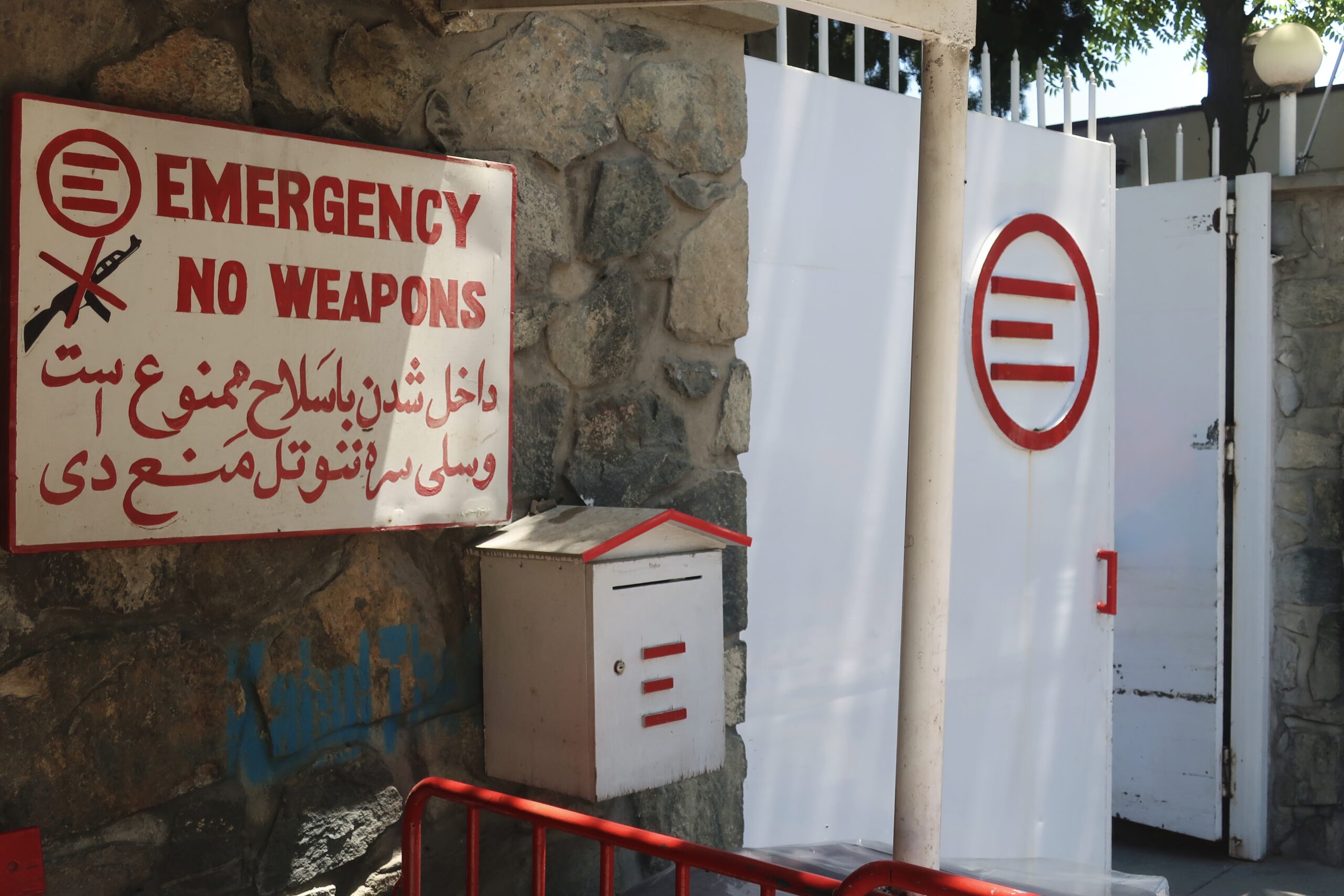 « Pas d'armes », en anglais, en dari et en pachto, à l'entrée de l'hôpital d'Emergency à Kaboul. L'ONG italienne, présente en Afghanistan depuis 1999, y soigne les blessés de guerre sans distinction de camp. © Nicolò Sancassiani.