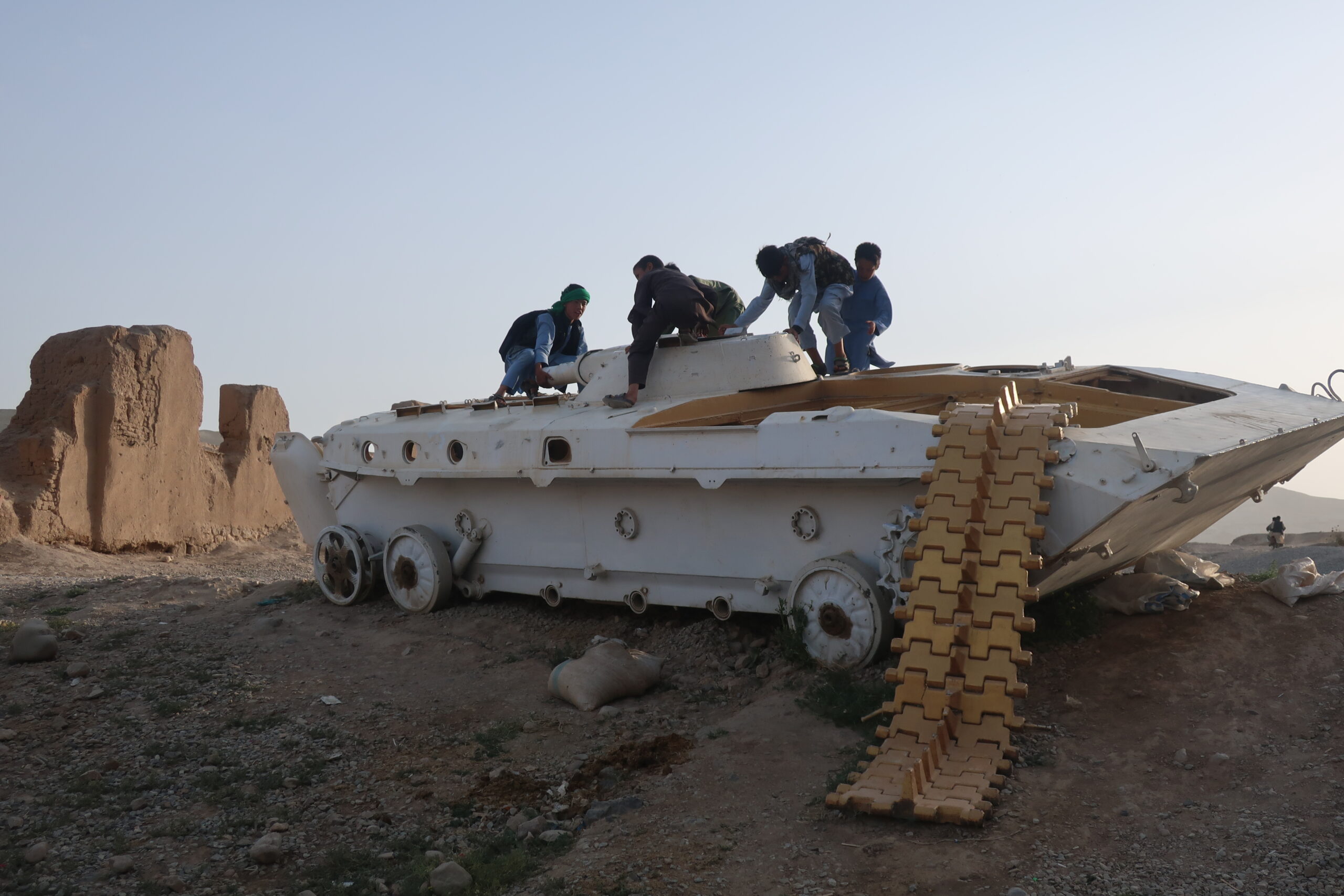 Des enfants jouent sur la carcasse d'un blindé de transport de troupes soviétique. Quatre guerres ont laissé leur ferraille dans le paysage afghan. © Nicolò Sancassiani.
