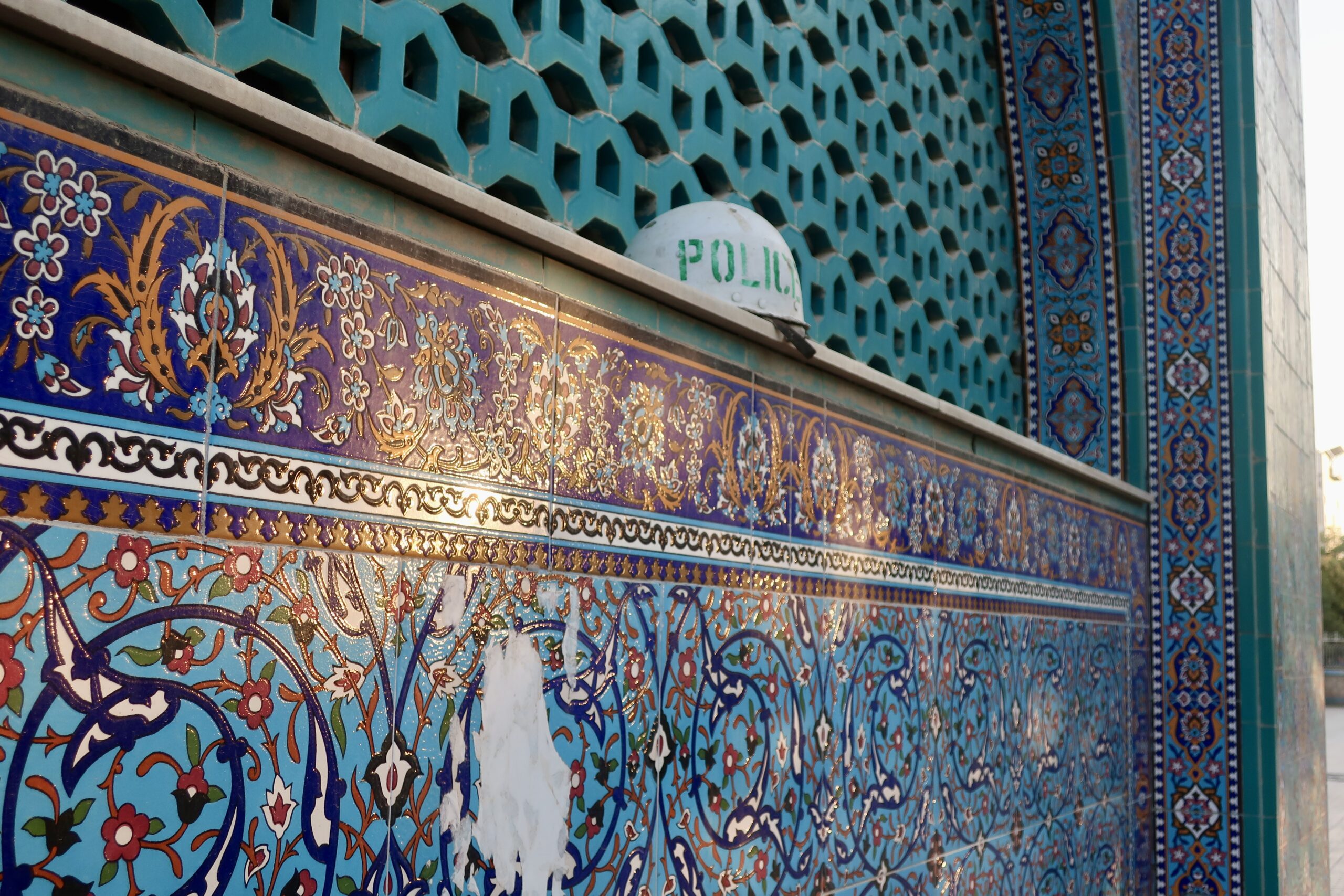Un casque de policier accroché à la façade de céramique d'une madrasa. Depuis 2021, le nombre d'écoles coraniques enregistrées est passé de 5 000 à plus de 23 000, presque toujours par reconversion de bâtiments existants. © Nicolò Sancassiani